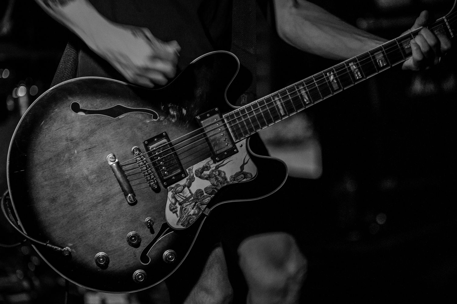 Close-up of vintage electric guitar being played in dark concert setting.
