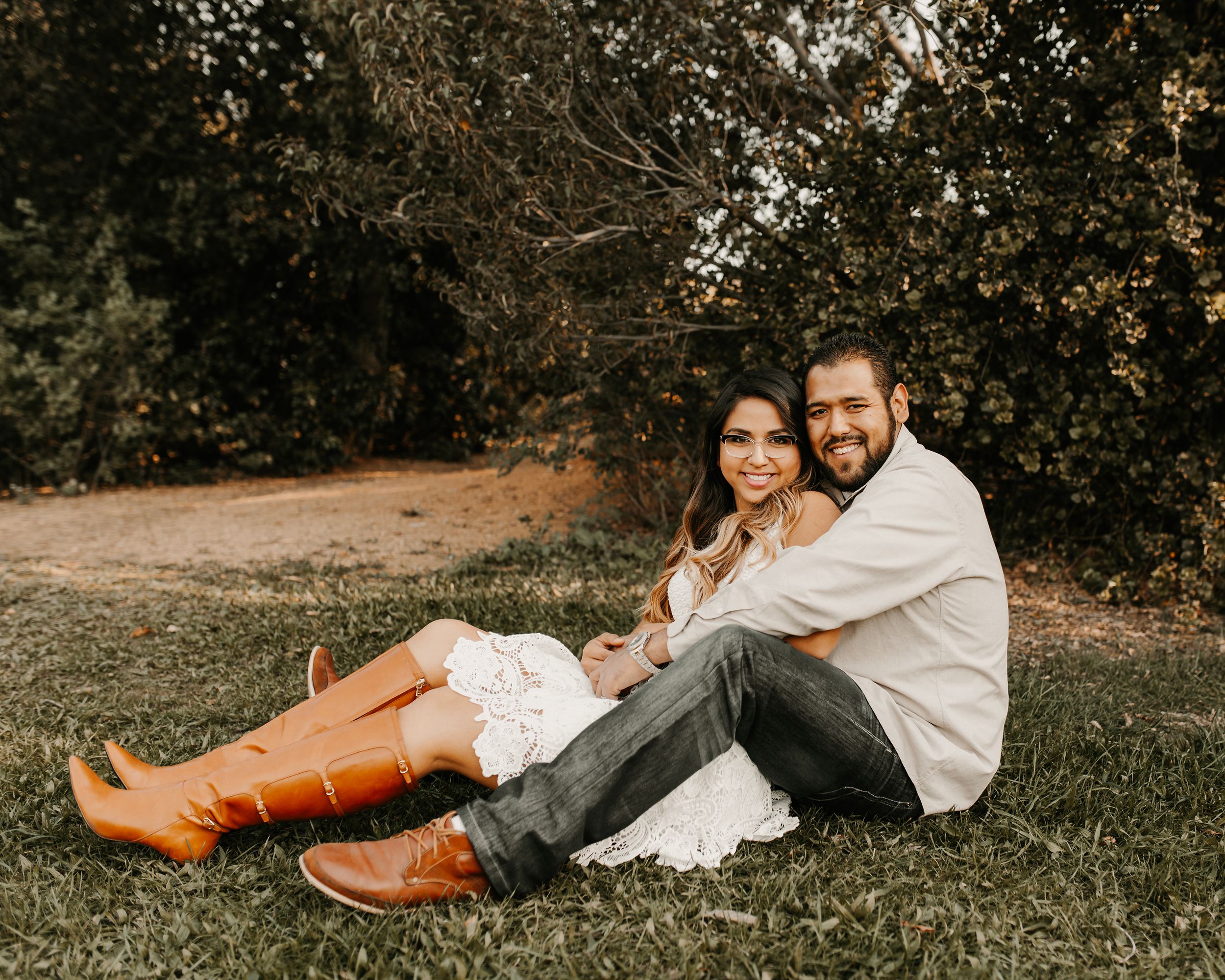 Casual outdoor couples photography with brown boots and white clothing on grass.