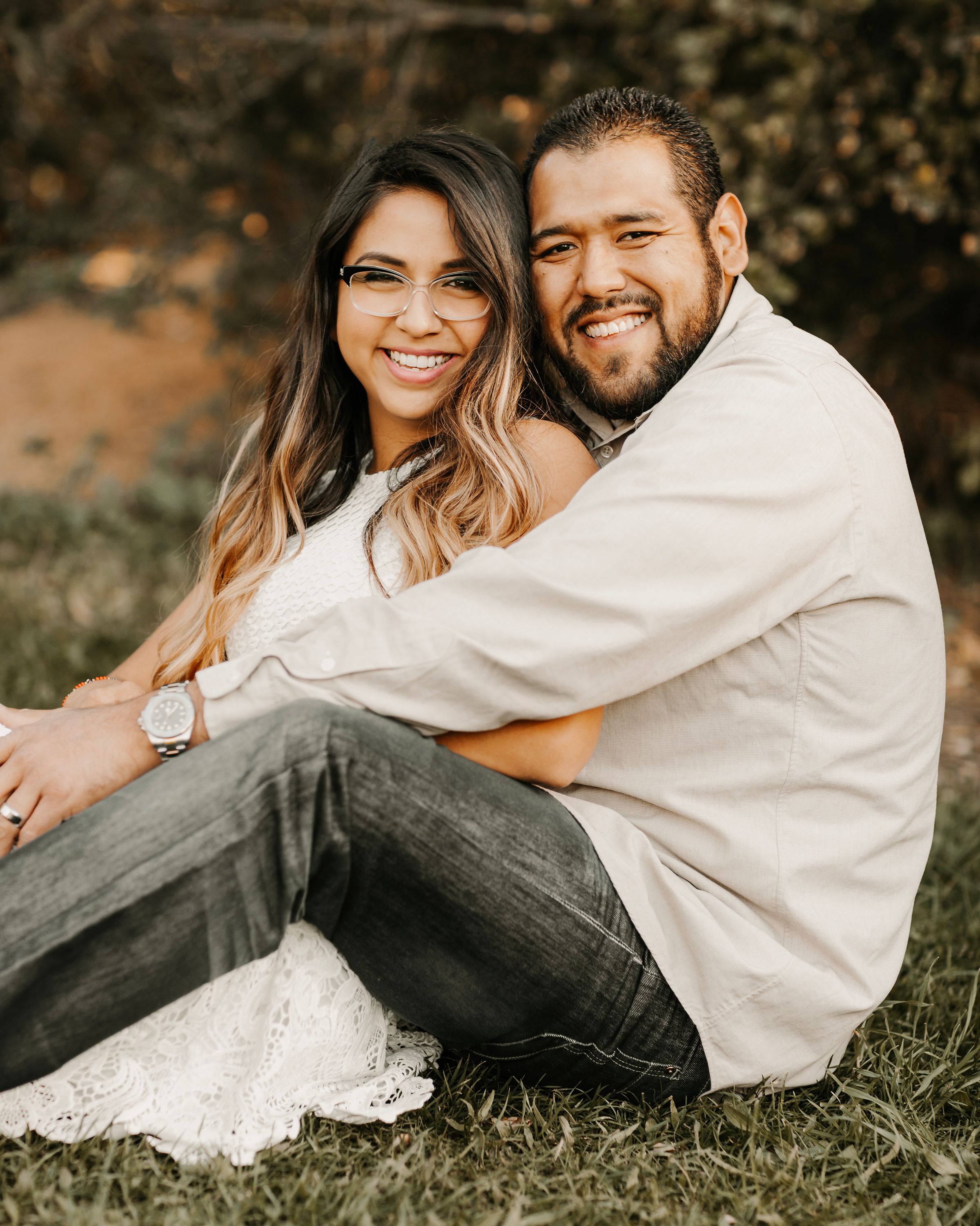 Romantic couples portrait session on grassy ground with natural autumn lighting.