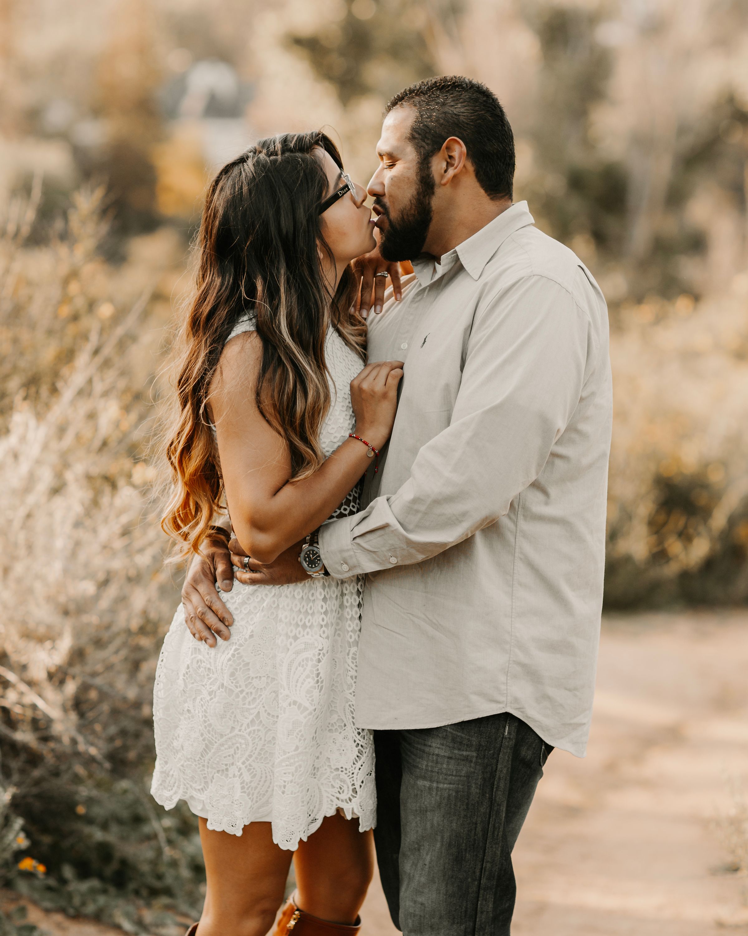 Romantic couple in white and gray outfits share intimate moments during outdoor photo session.