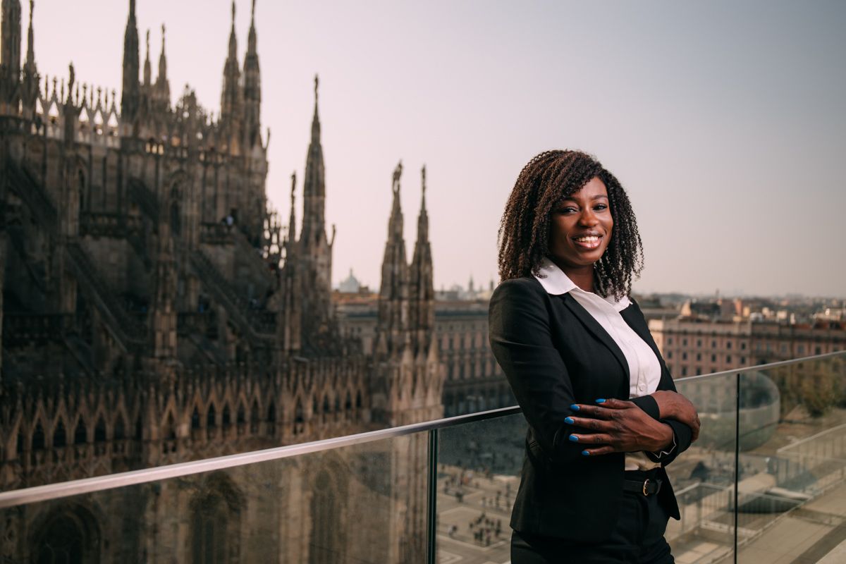 Business professional posing on balcony with Gothic cathedral spires in background.
