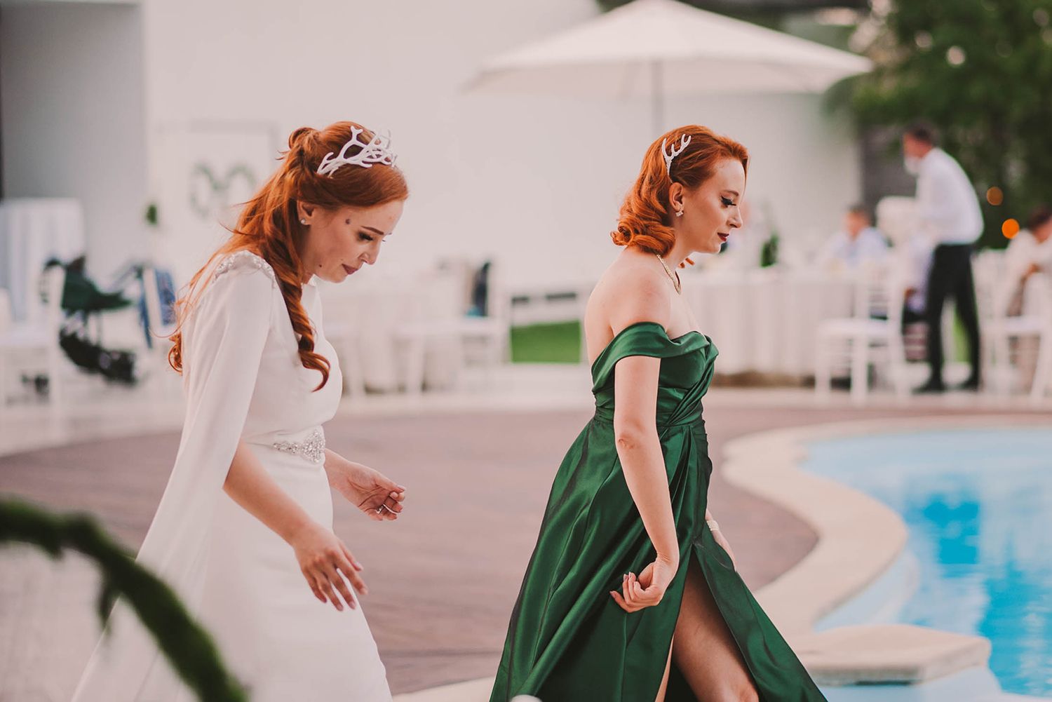 Wedding party dances on a patio near a swimming pool during evening celebrations.