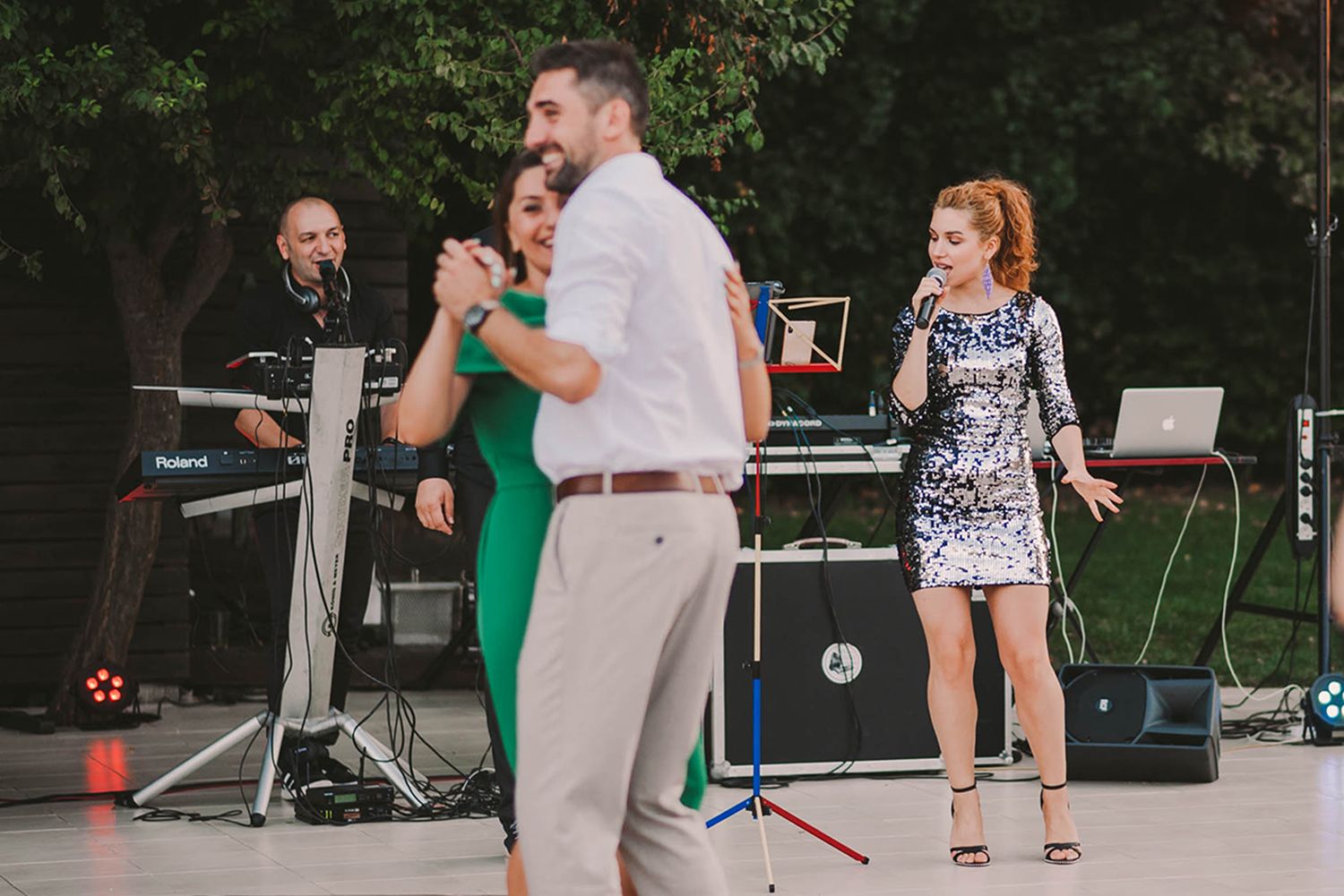 Wedding guests enjoy dancing on an outdoor patio during evening reception.
