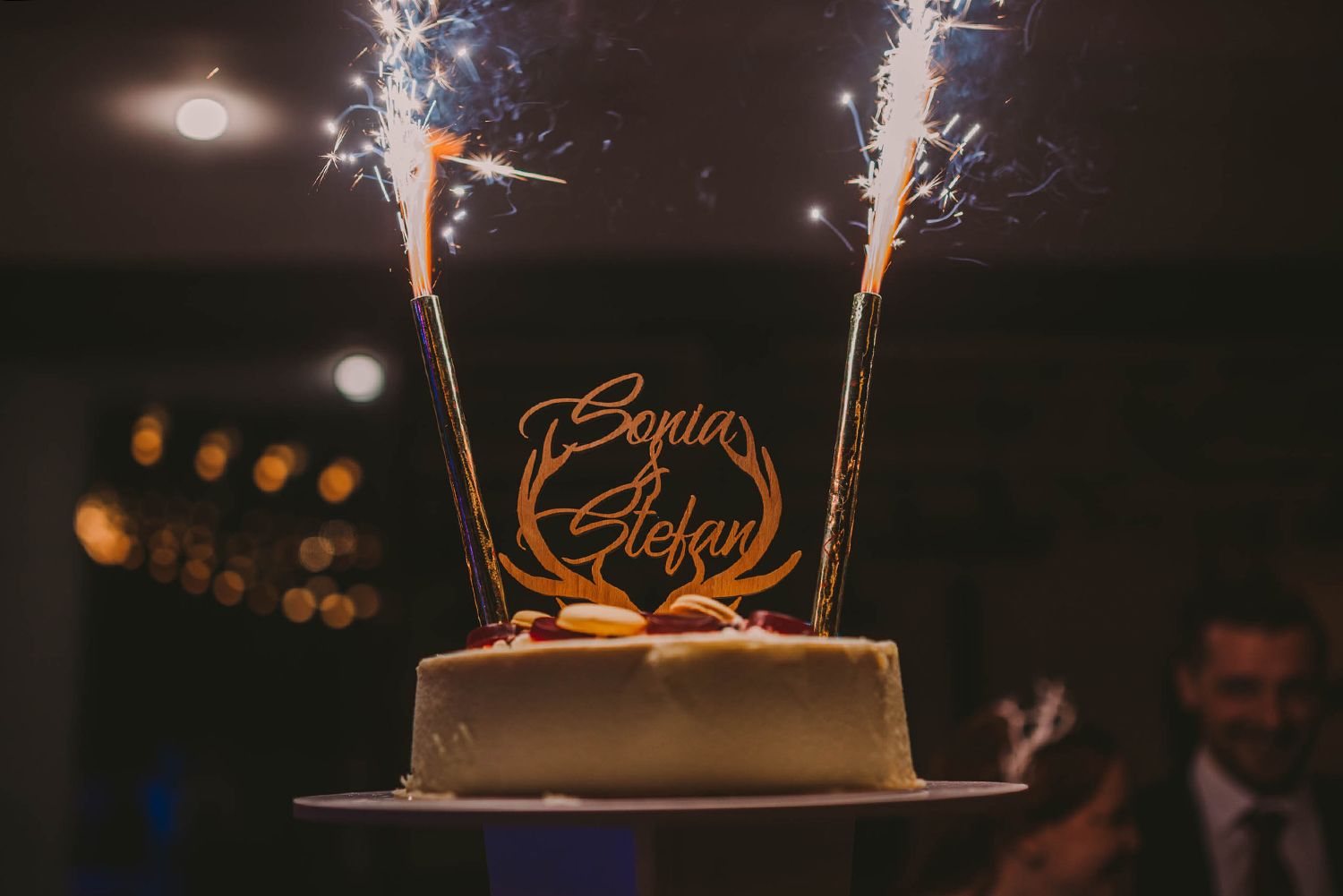 Sparklers illuminate a wedding cake during nighttime celebration.