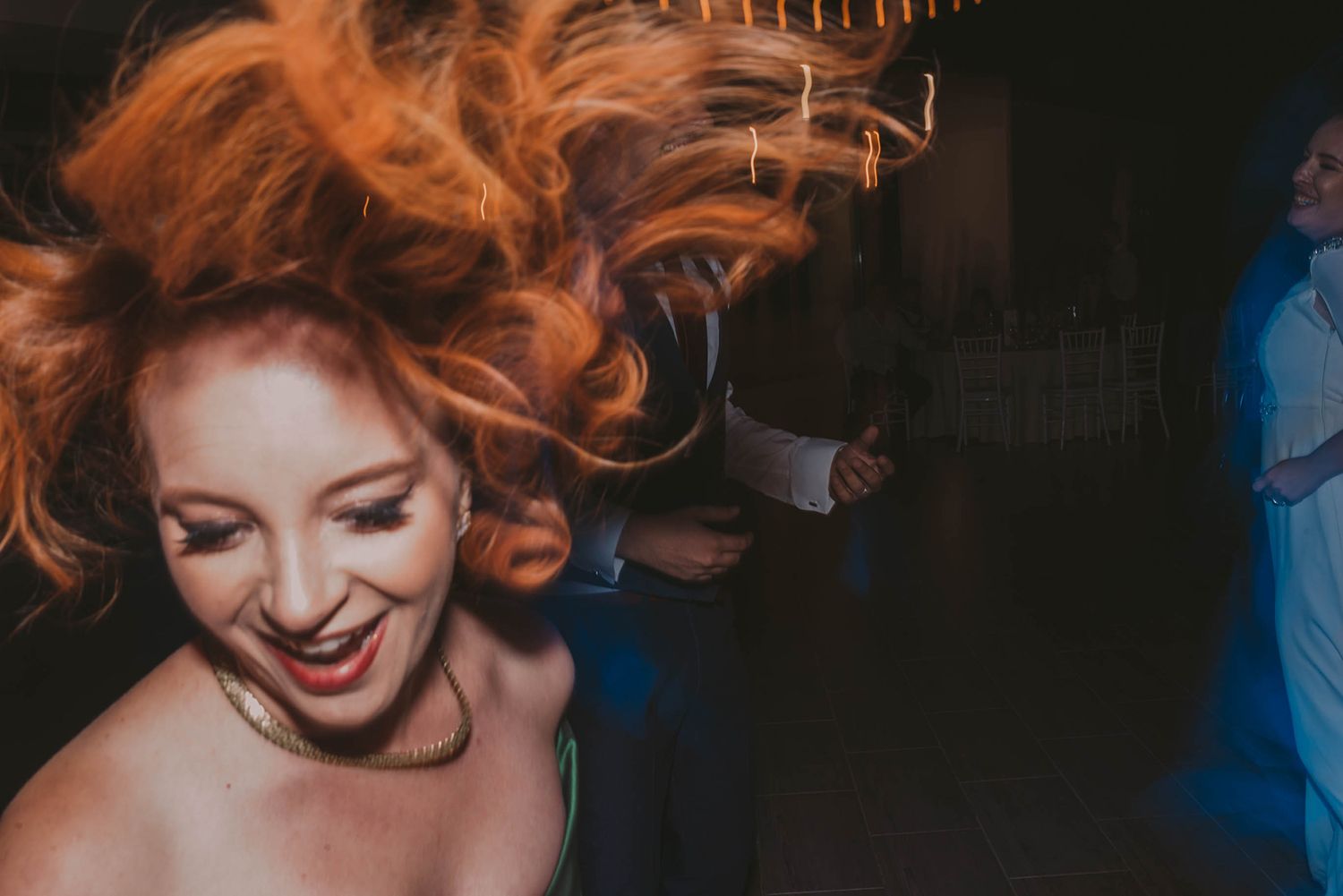 Dancing celebration captured in warm ambient lighting at wedding reception.