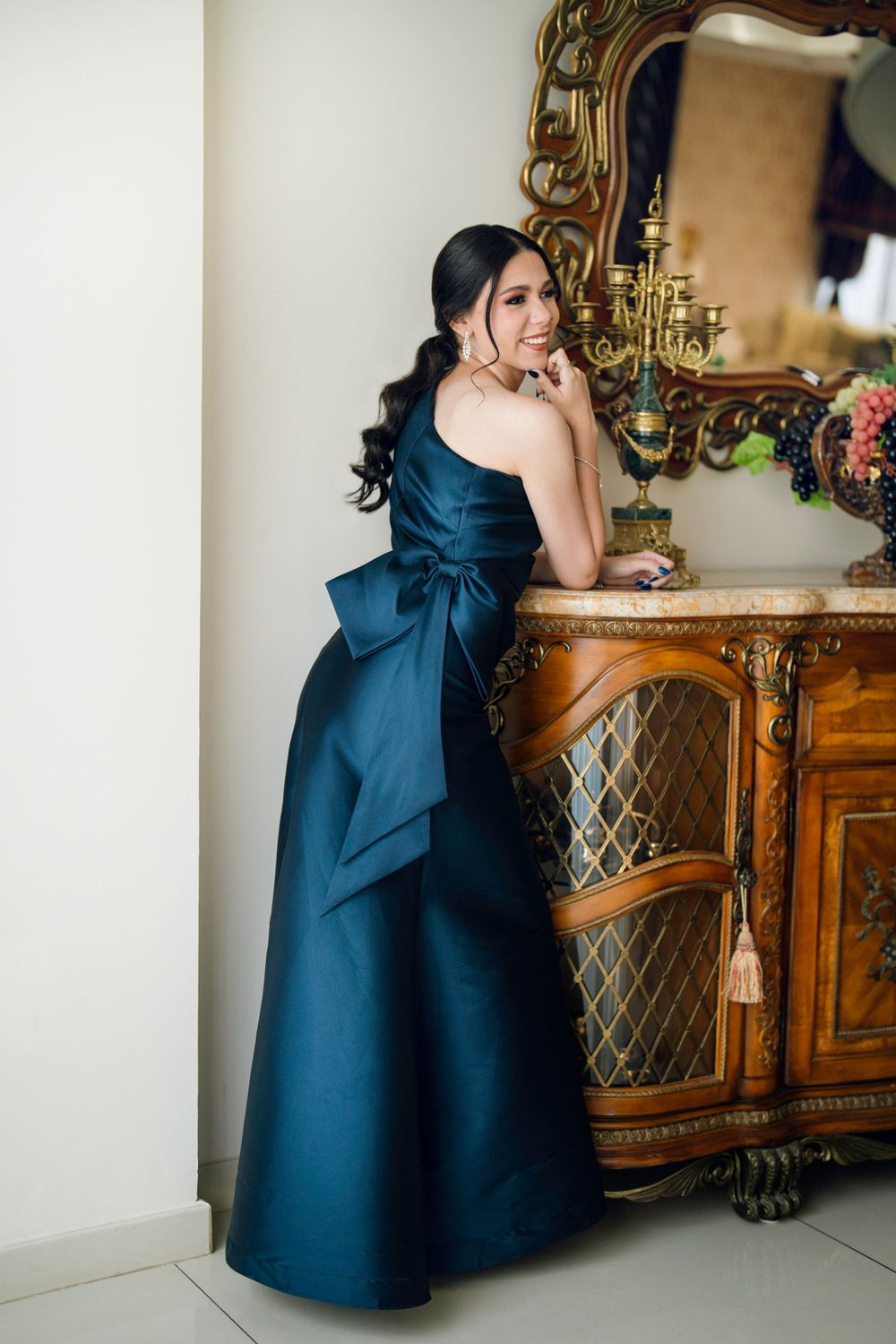 Elegant navy blue dress photoshoot with ornate vintage furniture and mirror backdrop.