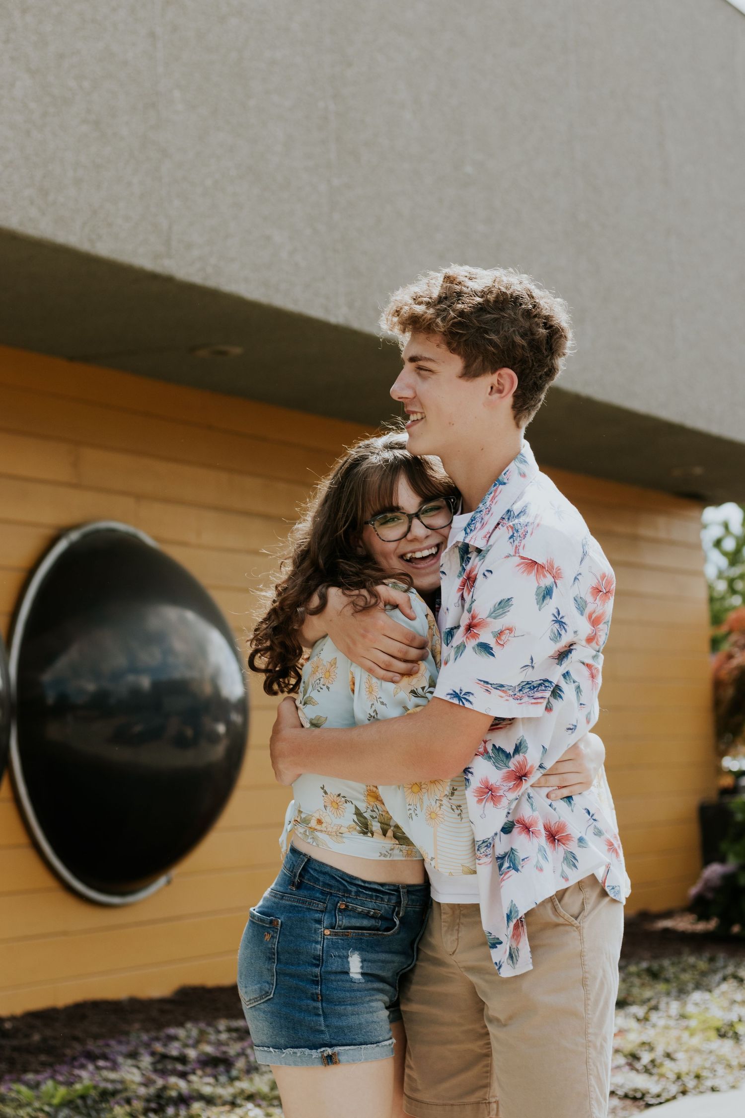 A couple sharing a joyful embrace in front of a yellow wall.