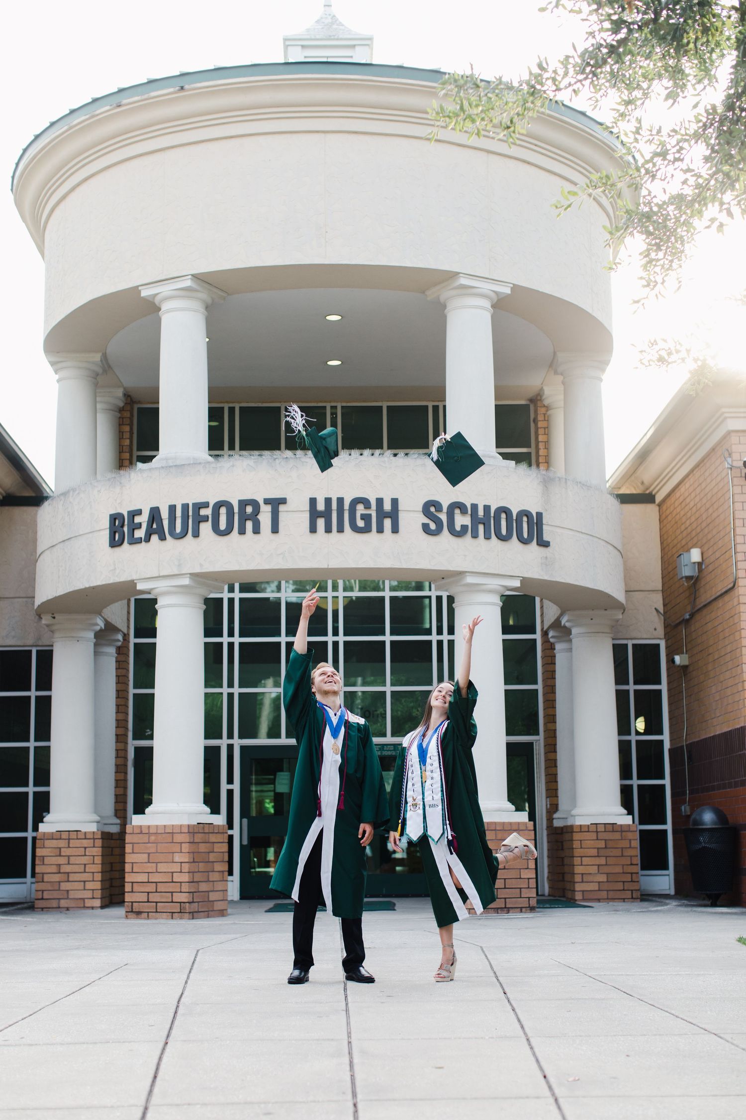 Graduates throwing caps in celebration at Beaufort High School entrance.