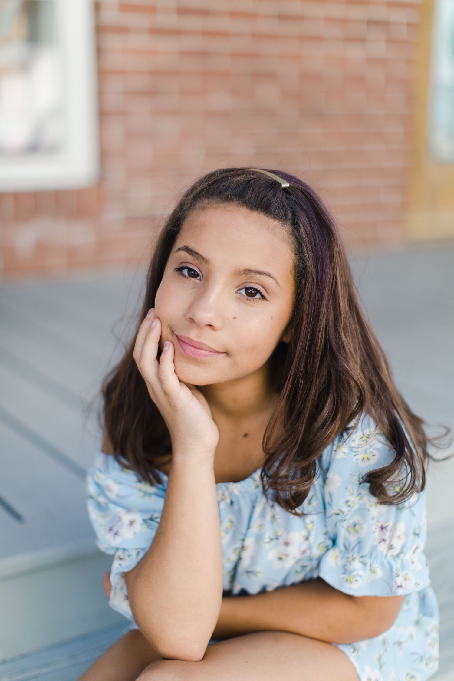 Portrait of person in blue floral top resting hand on chin.