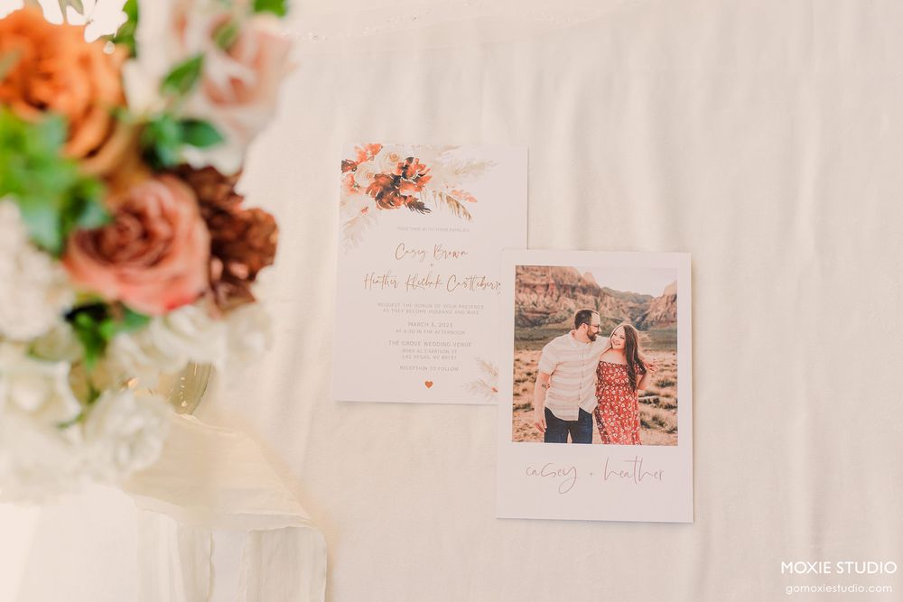 Wedding stationery and floral arrangements displayed on a white surface with soft pink accents.