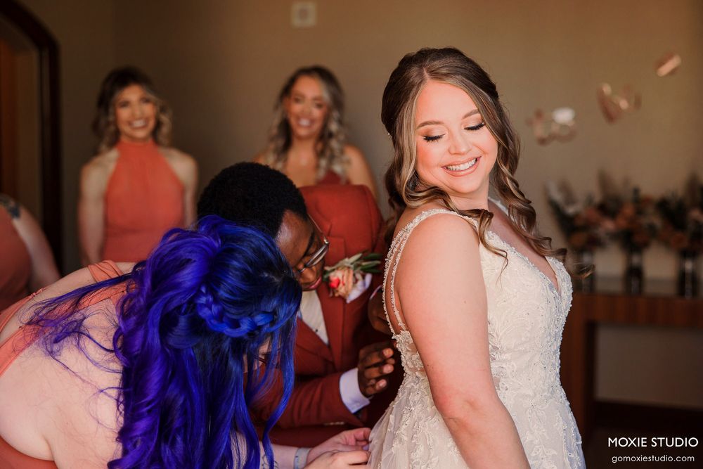 Wedding celebration features bright coral dresses and festive blue feather boas during dance party.