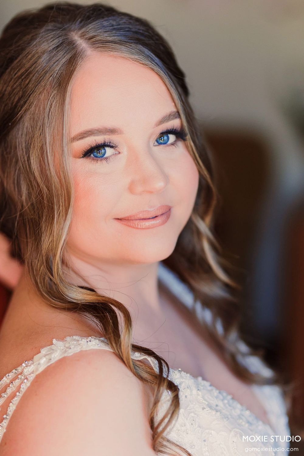 Beautiful bridal portrait showcasing soft makeup, wavy brown hair, and a delicate lace wedding dress.