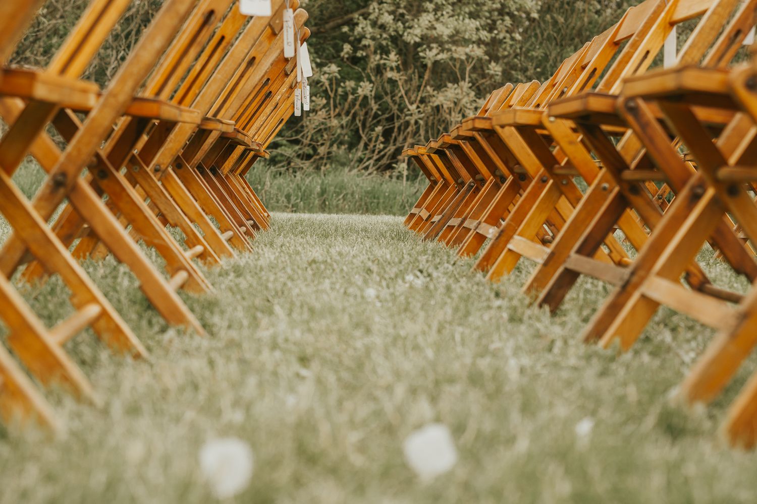 Wooden folding chairs arranged in rows on grass creating an outdoor ceremony aisle in southern Michigan.