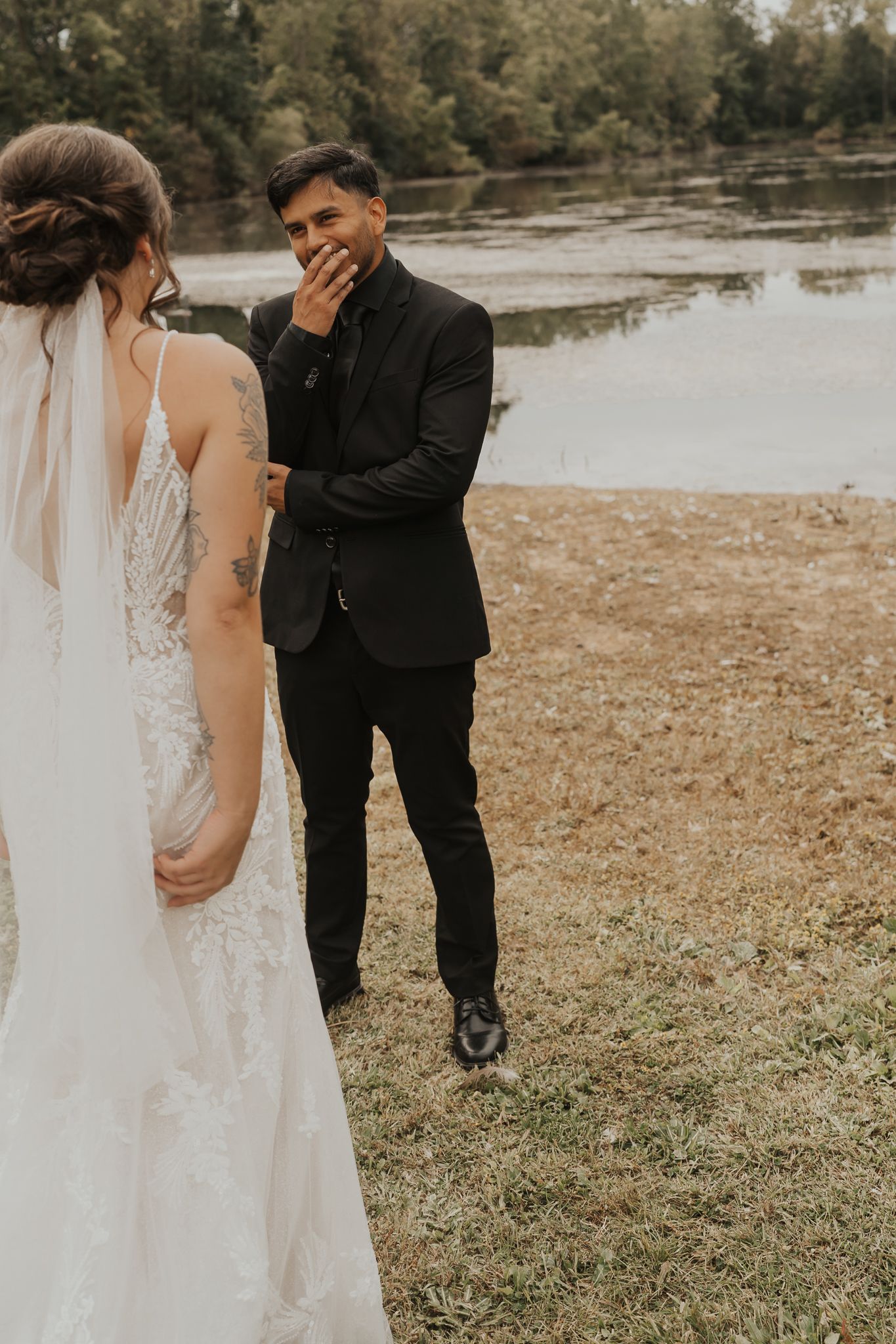 Wedding couple sharing a tender moment by a lake on their special day.