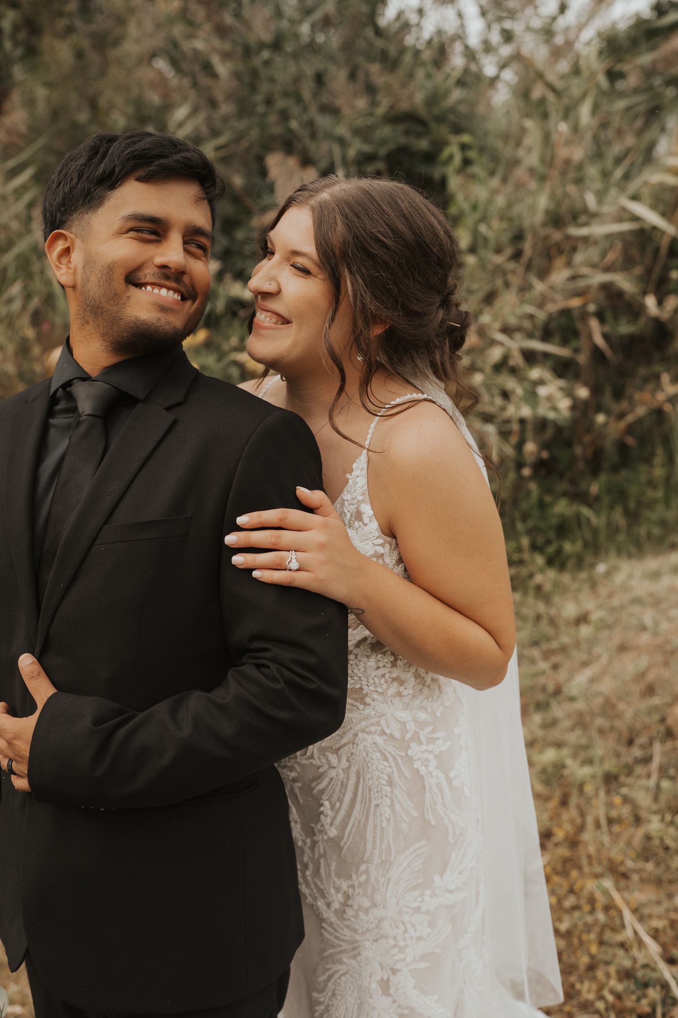 Joyful candid moment between newlyweds during outdoor wedding portraits.