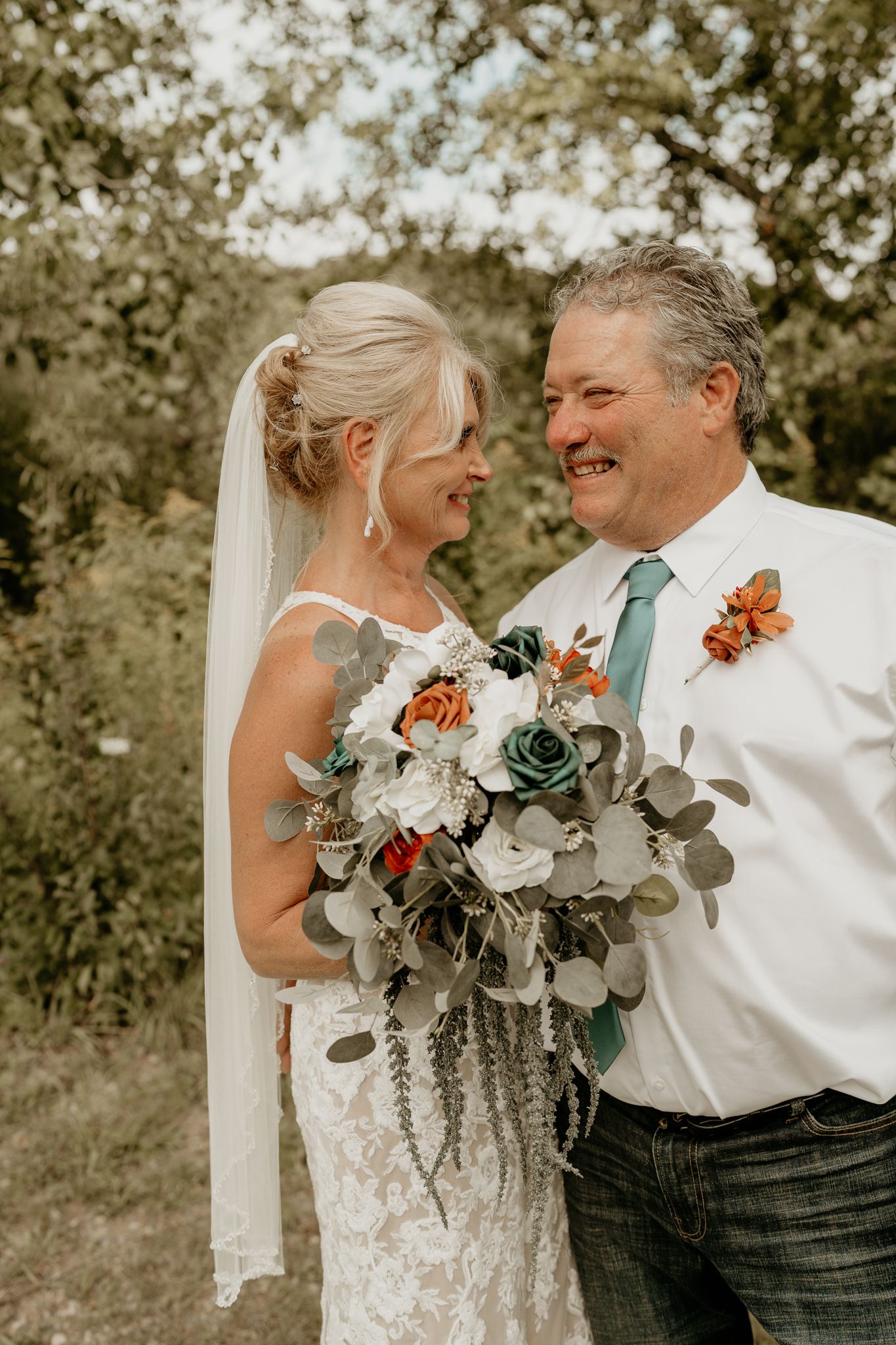 An intimate wedding portrait series showing candid laughter and smiles between a couple with floral arrangements.