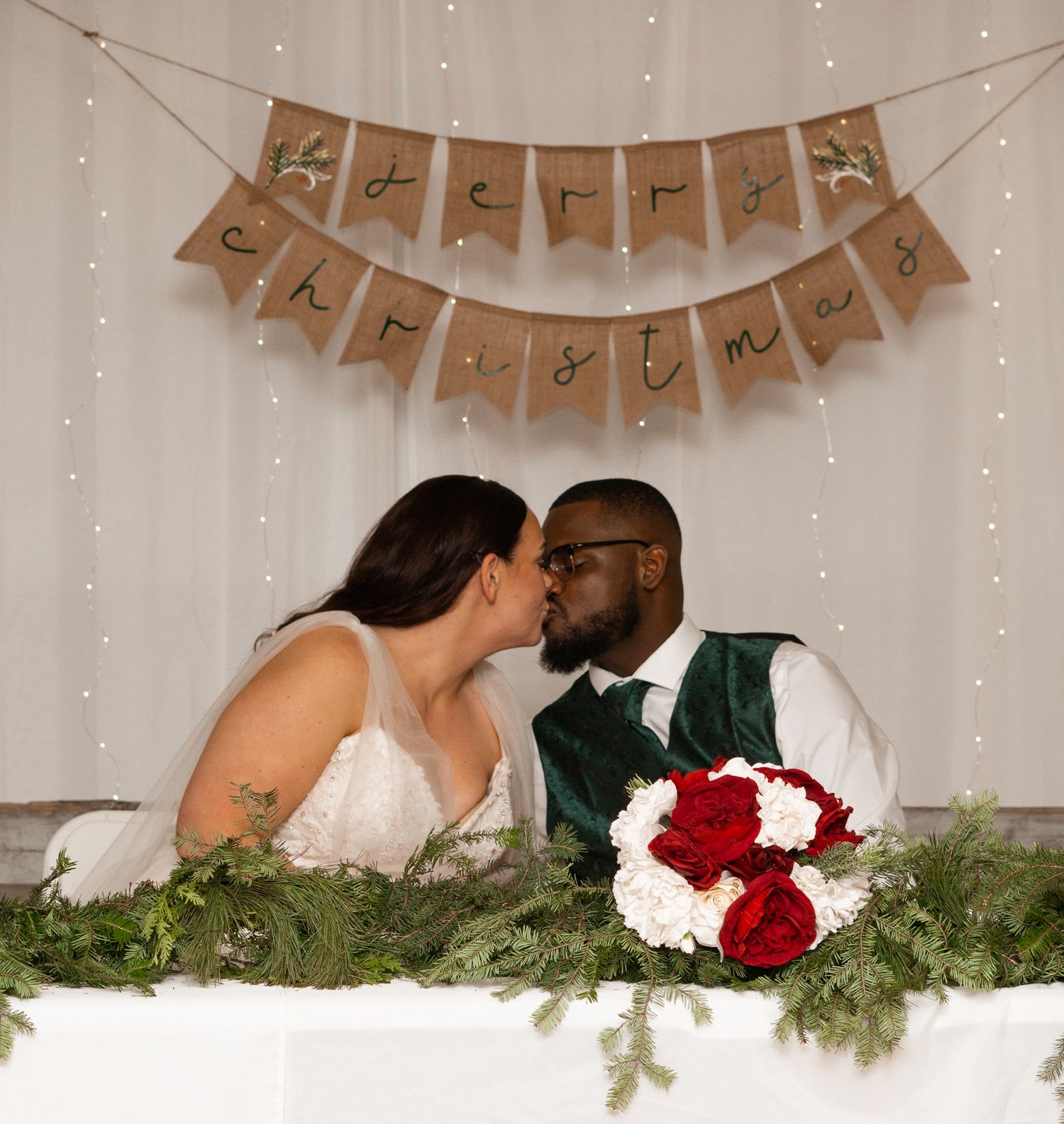 A couple shares an intimate moment at their Michigan reception table decorated with greenery and fairy lights.