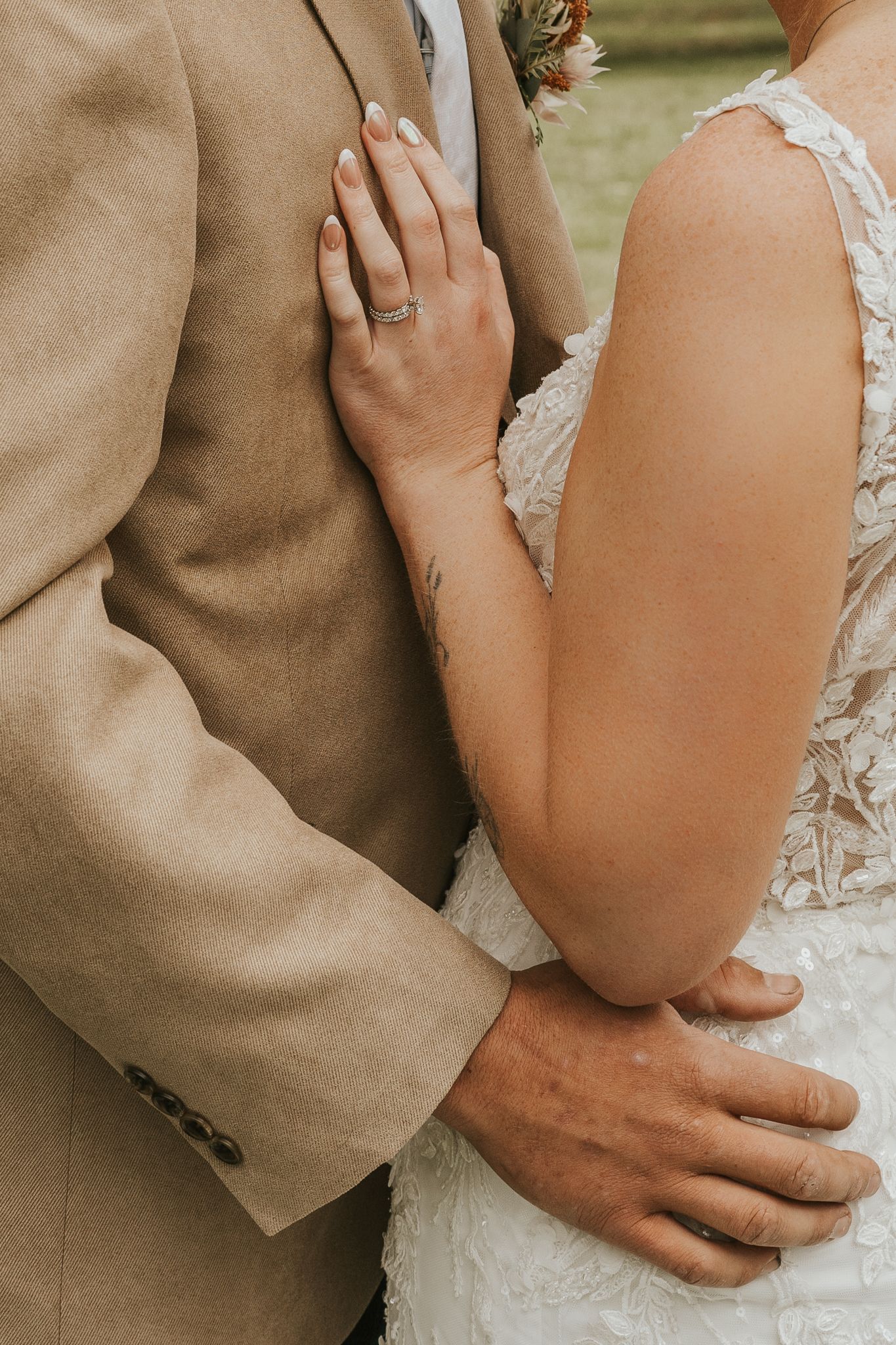 Close-up detail of couple embracing in formal wedding attire.
