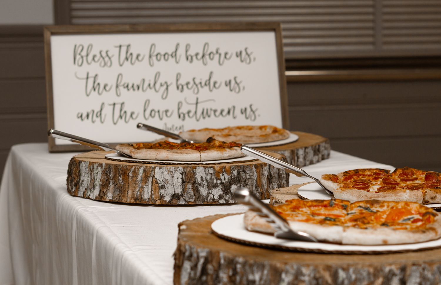 Rustic wood slice platters with food and inspirational quote sign at wedding reception.