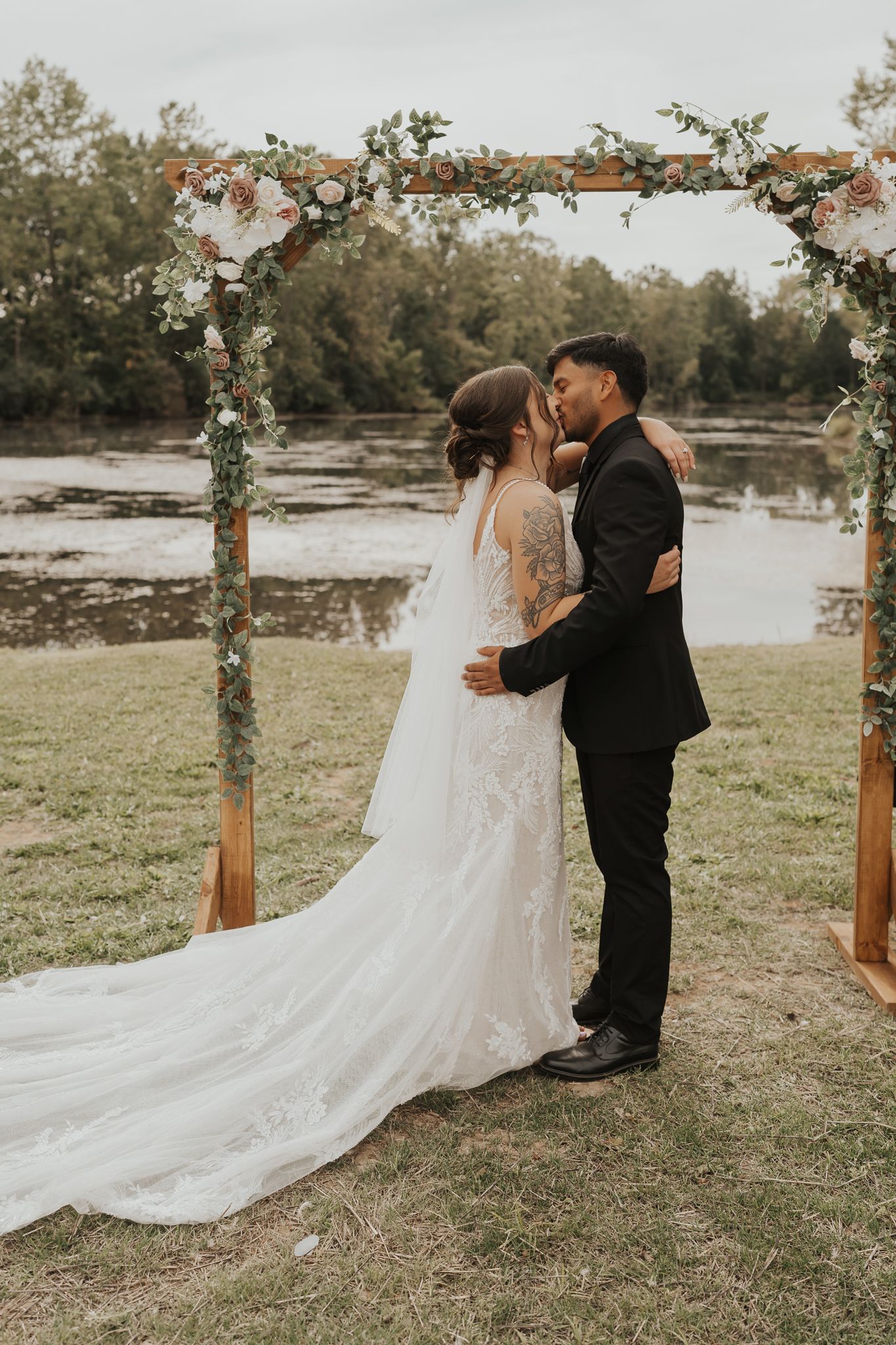Romantic wedding ceremony under a floral arch by Michigan waterfront.
