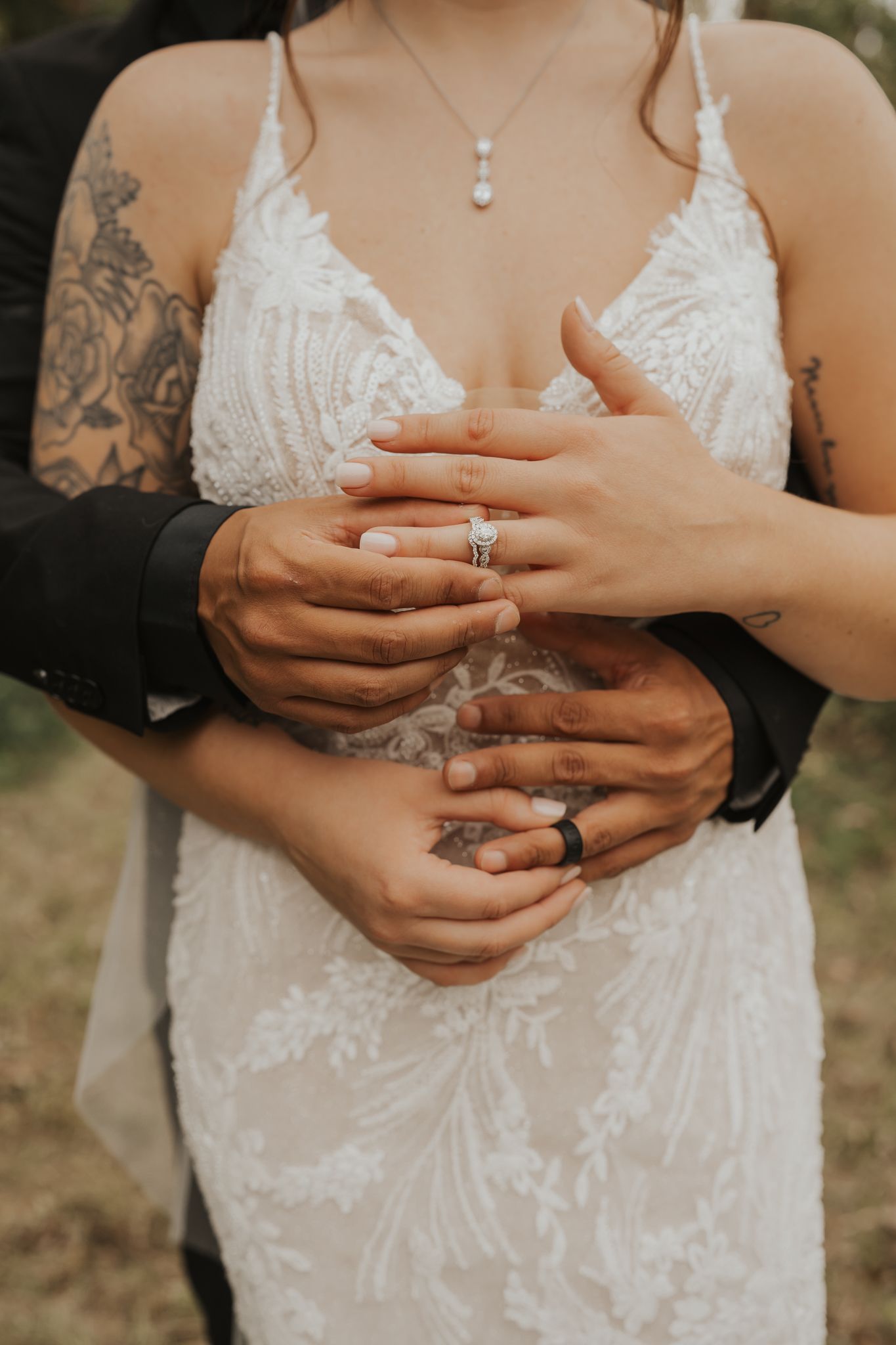 Close-up of wedding rings and lace details on a bridal gown.