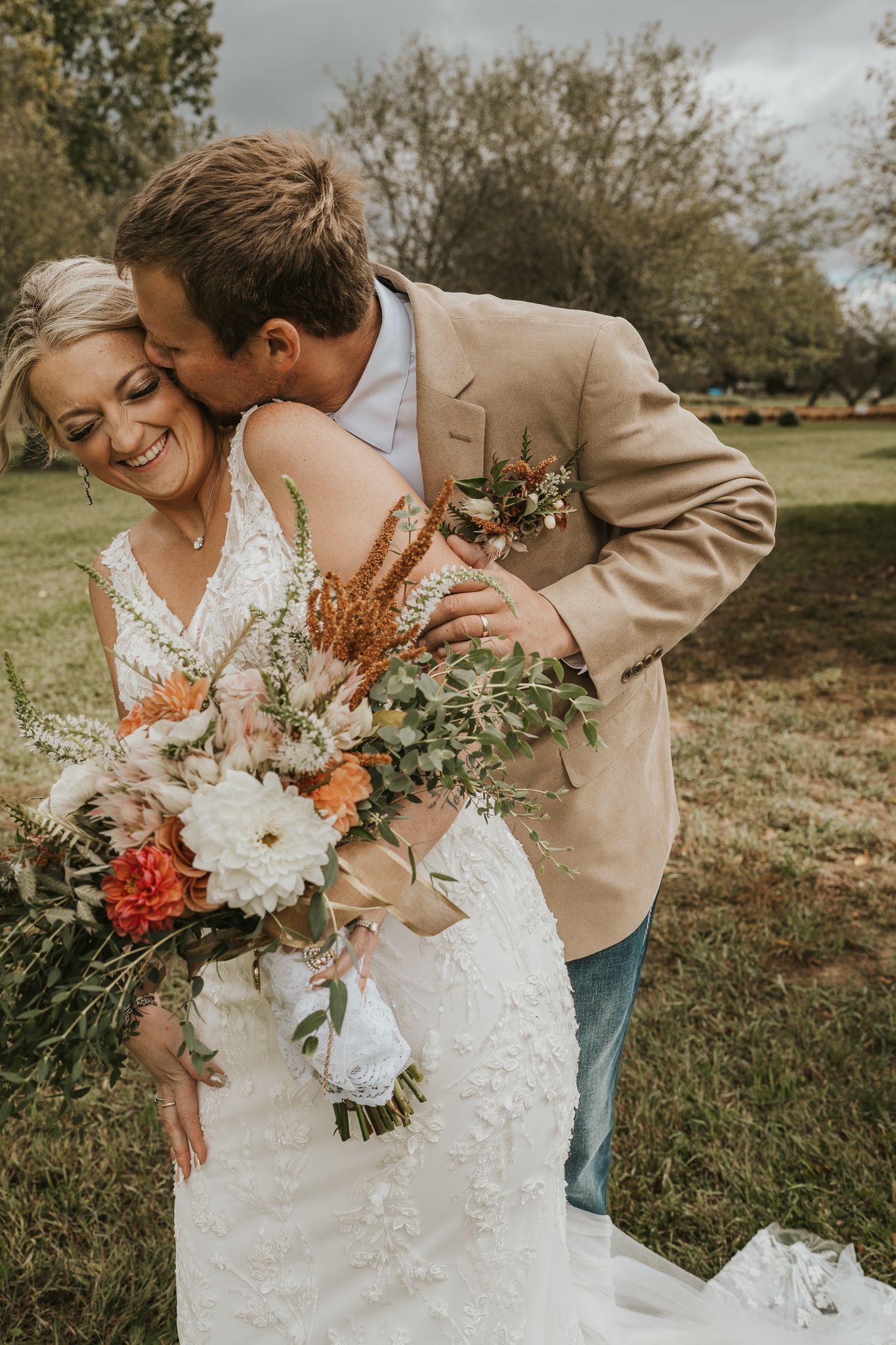 Bride holding autumn bouquet shares intimate moment with groom in outdoor garden setting.
