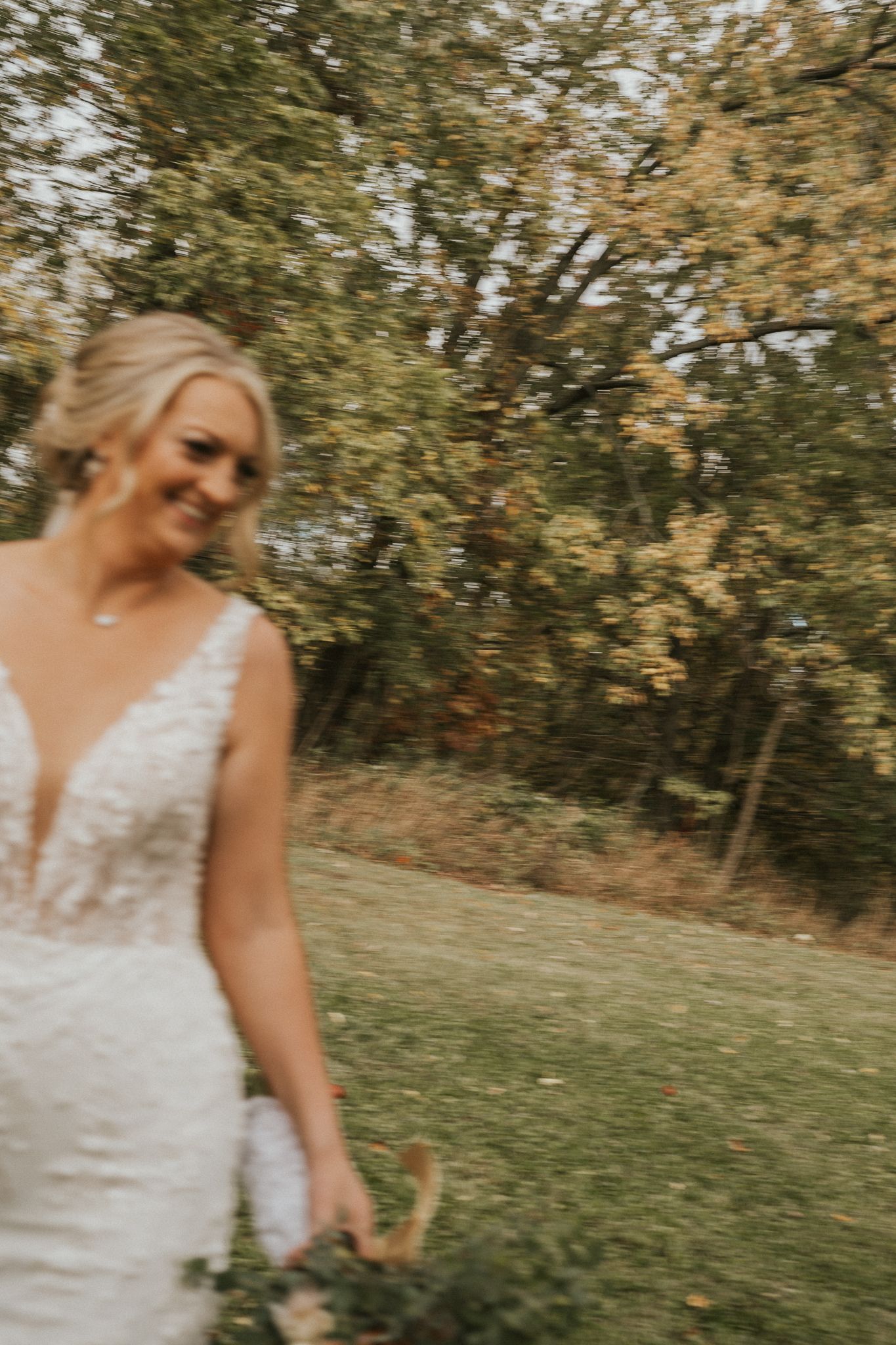 Bride in lace dress walks through an autumn garden setting.