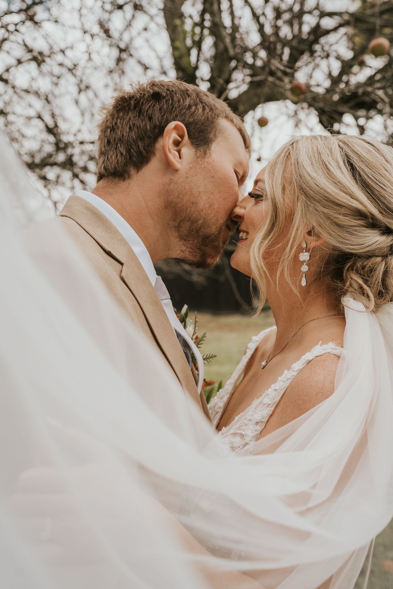 Intimate close-up of couple sharing a tender moment under a flowing veil.
