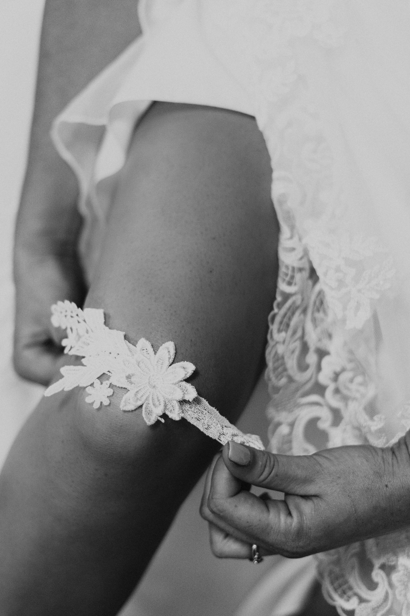 Close-up of a delicate lace garter being placed on a leg.