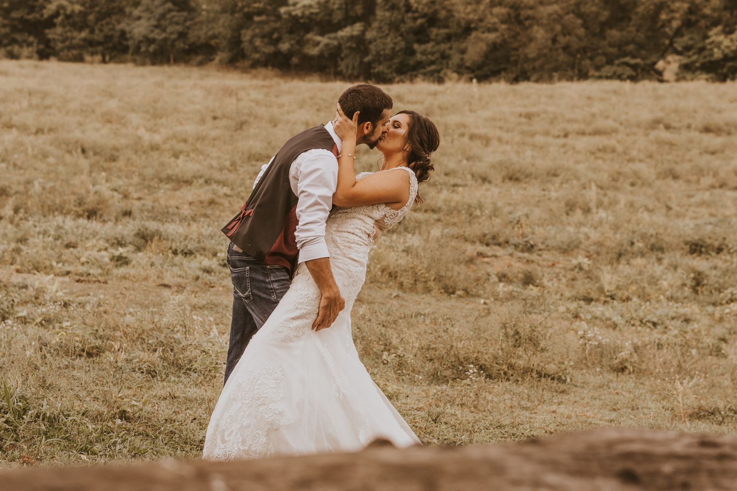 Wedding couple strolling through rustic field during golden hour photography session.