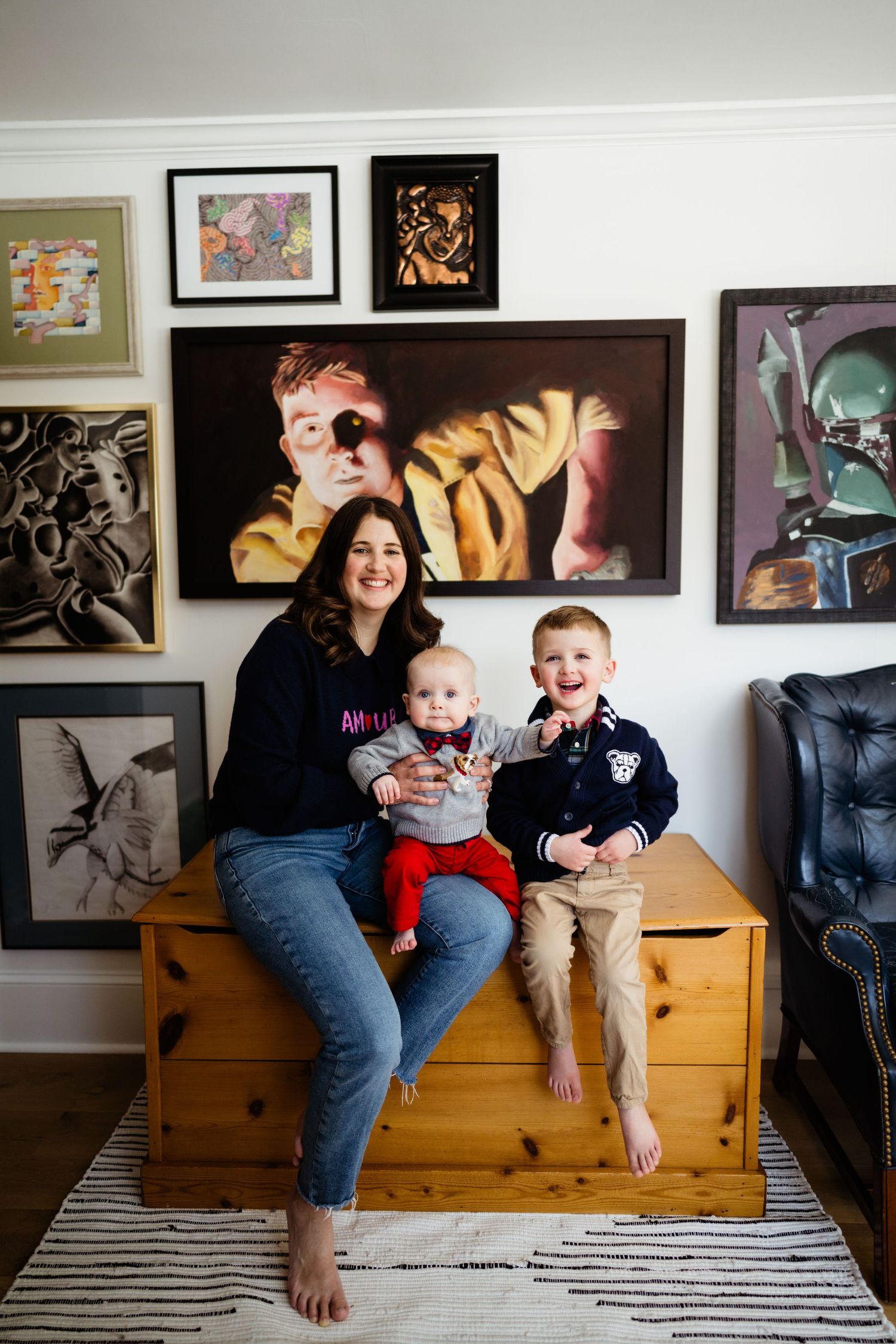 A family moment captured in front of an artistic gallery wall with colorful framed artwork.