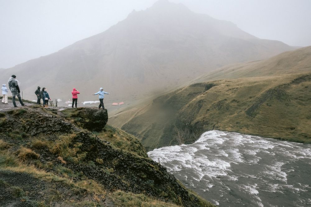 Dramatic mountain vista with waterfall and hikers viewing from a distant ridge.
