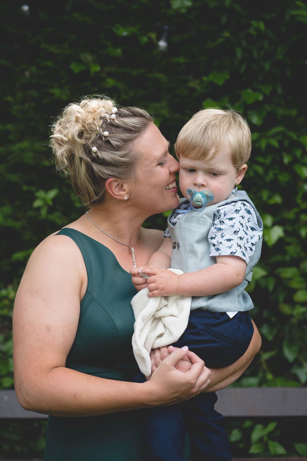 A tender moment captured between a woman in green and a small child outdoors.
