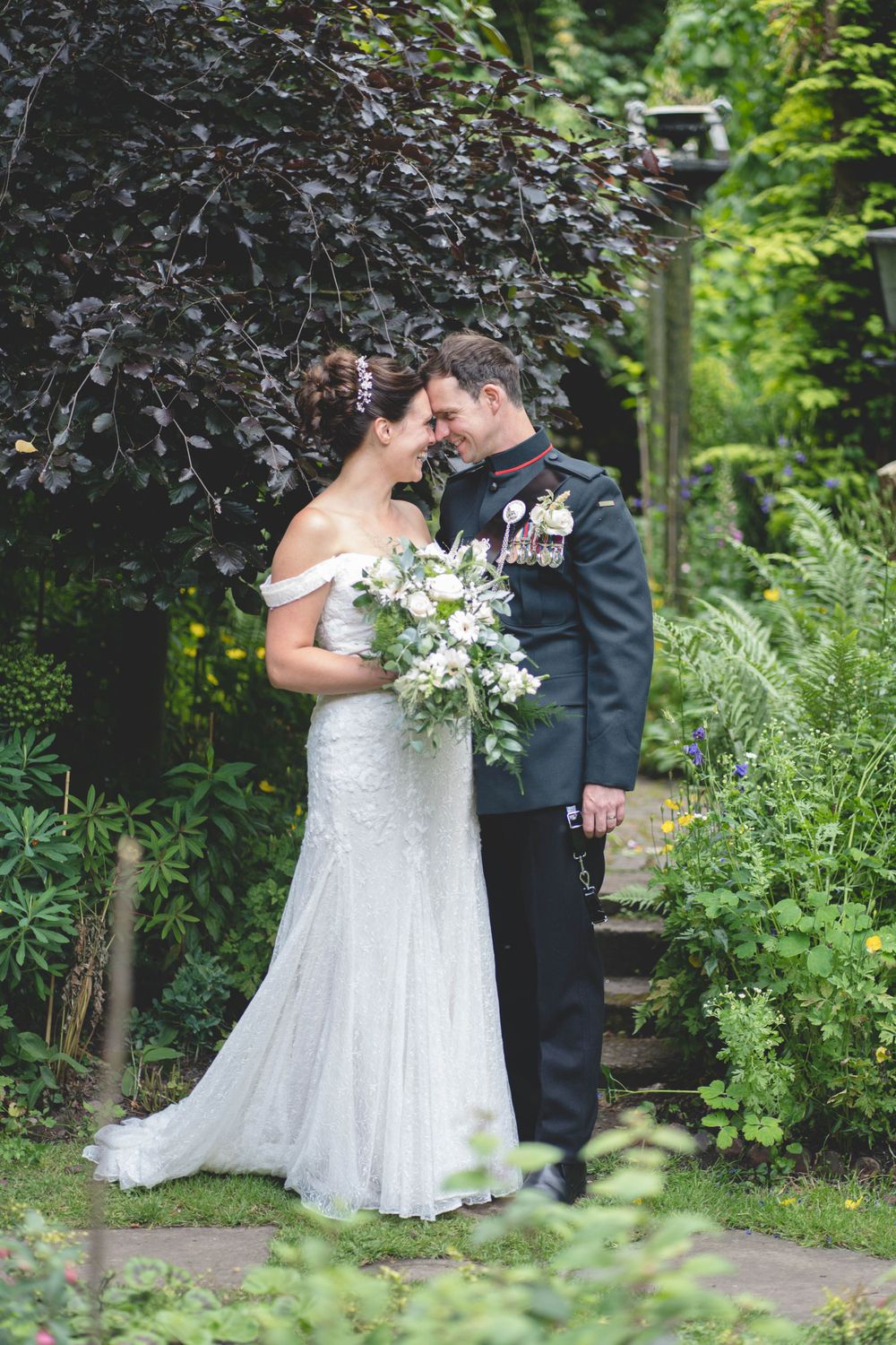 An intimate wedding portrait of a couple sharing a tender moment in a lush garden path.