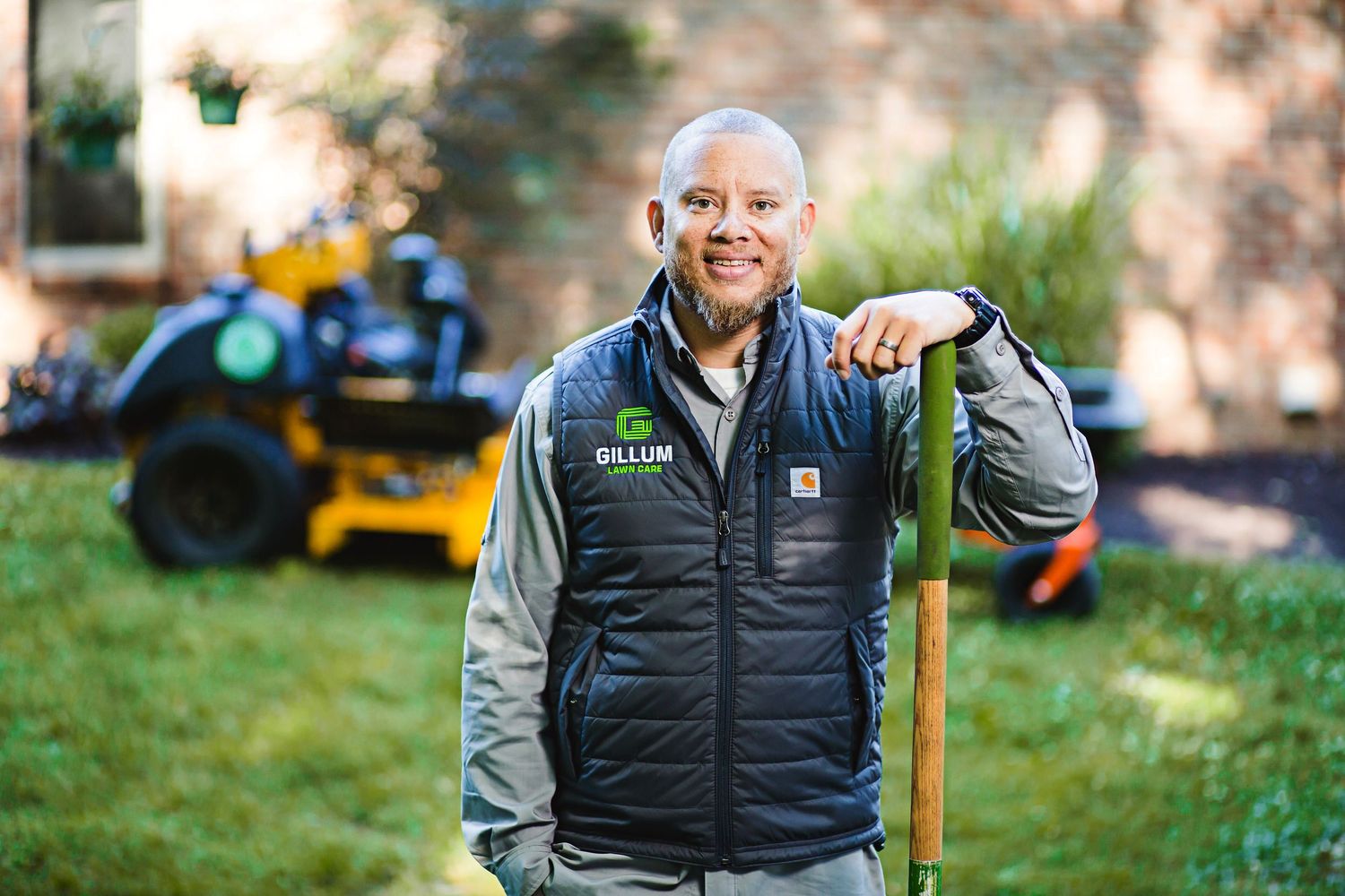 Outdoor portrait of maintenance worker in branded vest with equipment in background.
