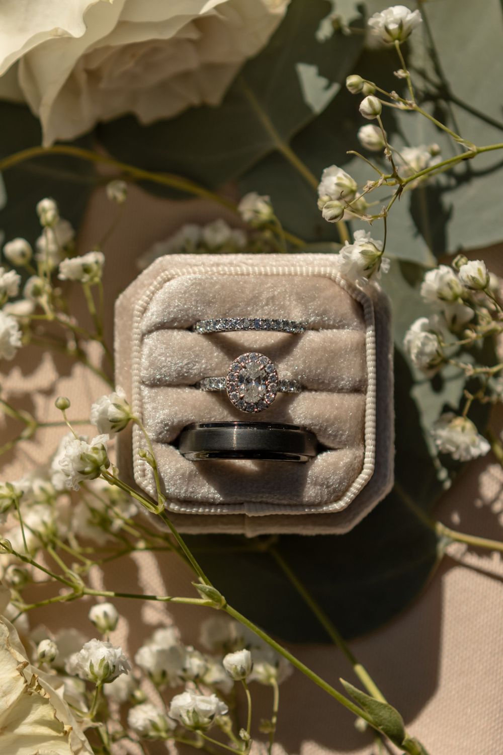 Ringbox photographed as a part of a flat lay for a wedding. The colors are nuetrals and greens, with floral details.