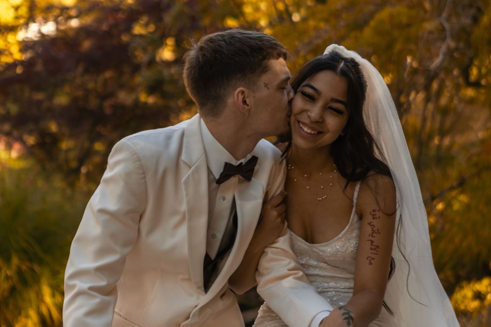 A new husband kisses his new wife on the cheek on their wedding day.