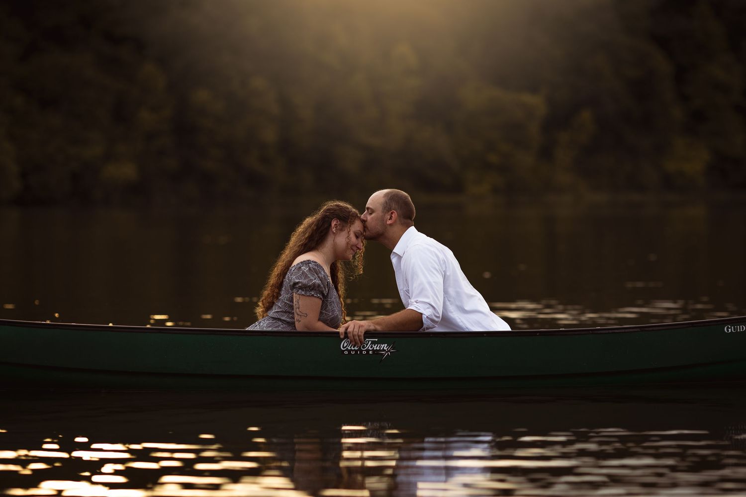 Young sweethearts kiss in the middle of a canoe sitting on a small pond outside of Charleston, Illinois.