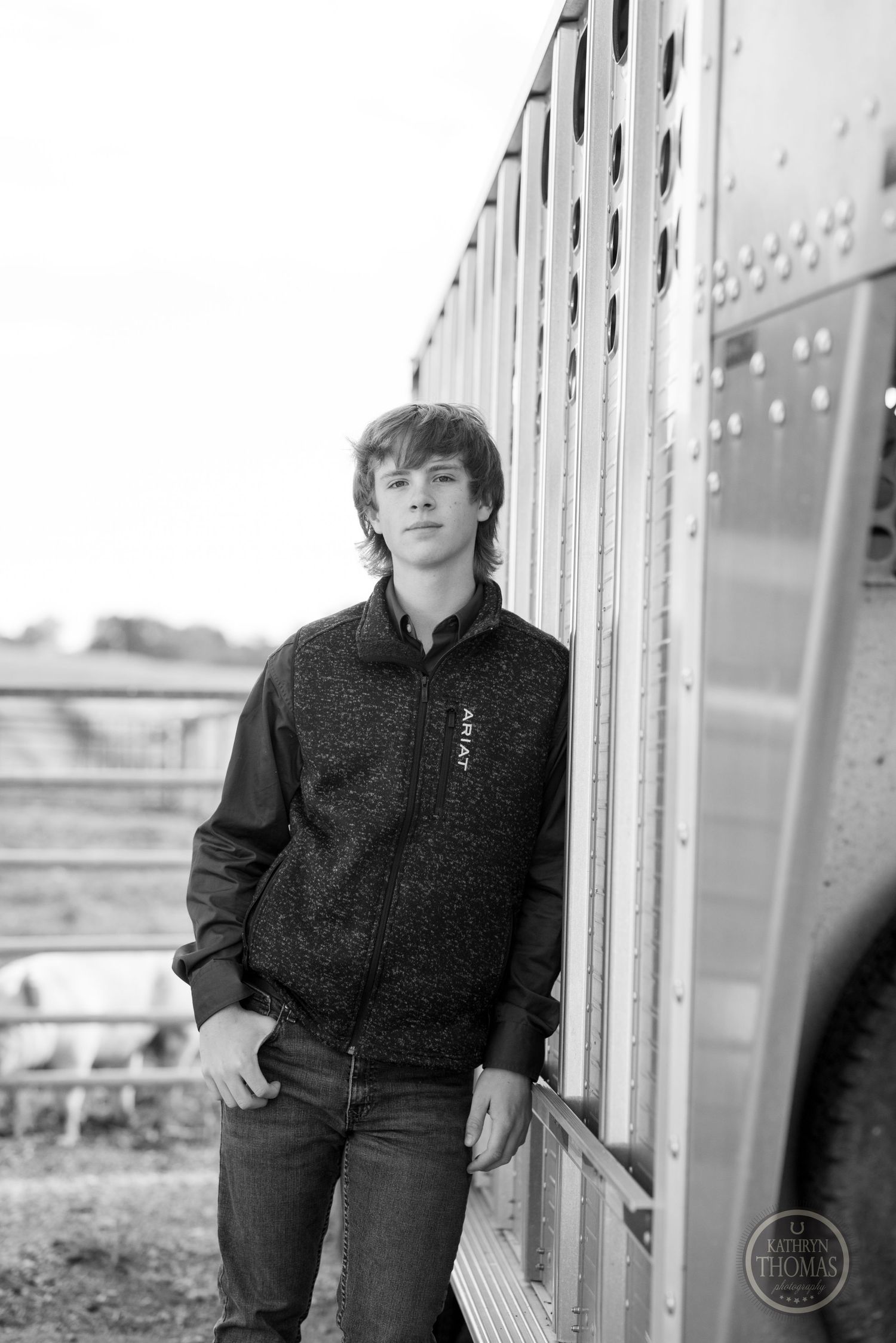 Black and white portrait of person standing beside metal train car or container.