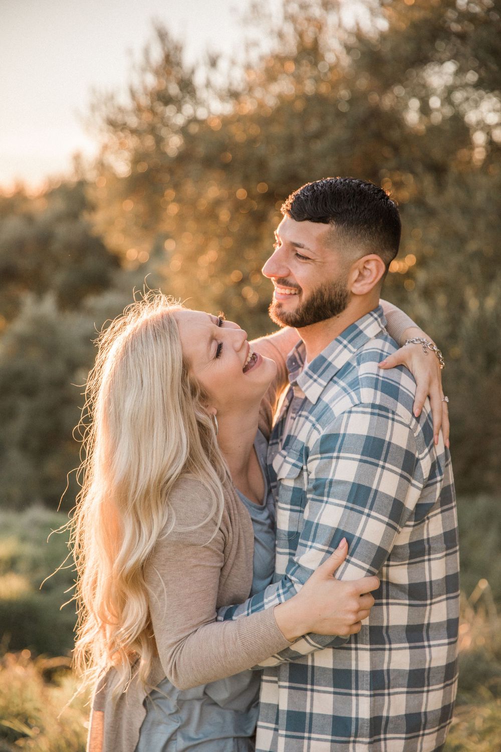 Mexican man and white woman hug each other in engagement portraits in Knight's Ferry, California