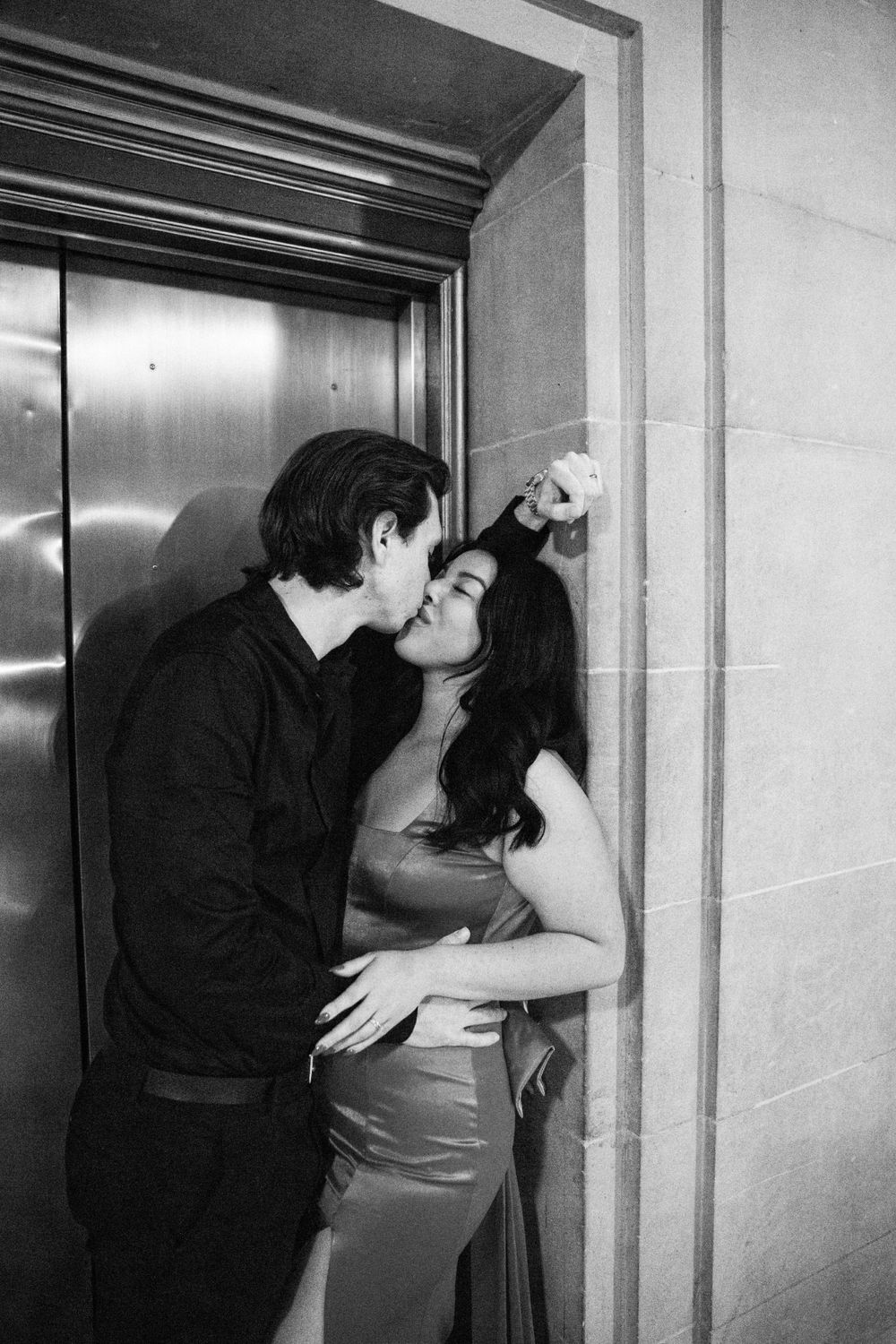 white man and Mexican woman embrace in elevator in San Francisco City Hall.