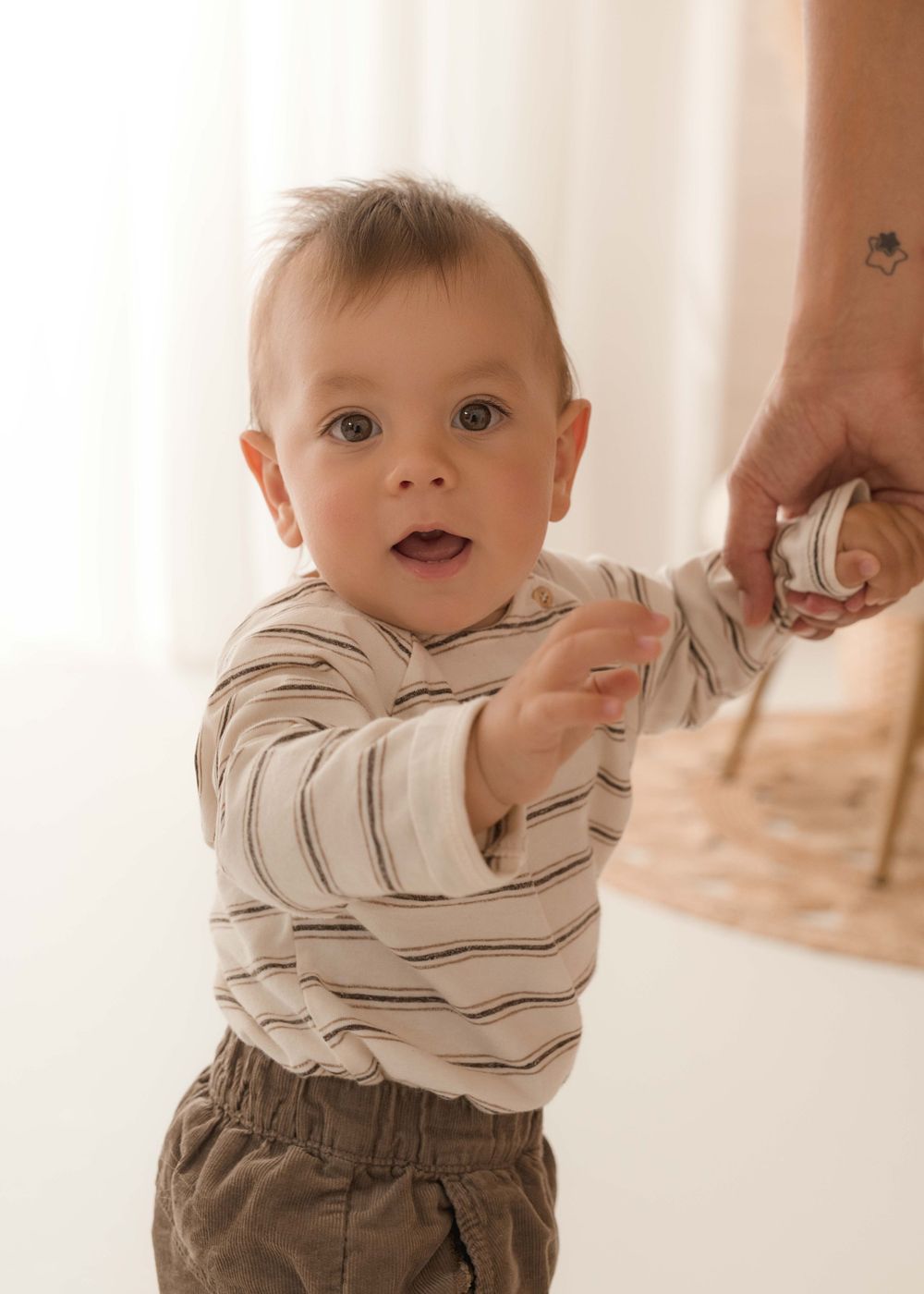 Baby in striped outfit showing expressions during professional photo session.
