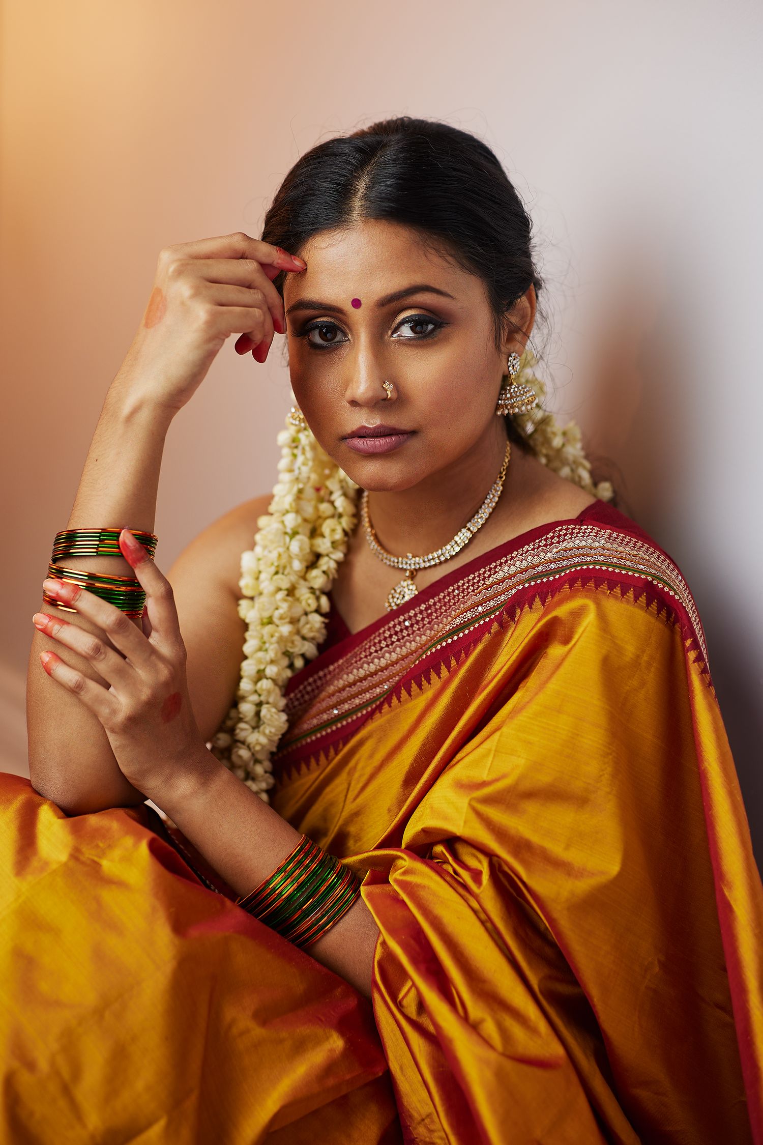 Traditional South Asian fashion portrait featuring golden silk saree and jewelry.