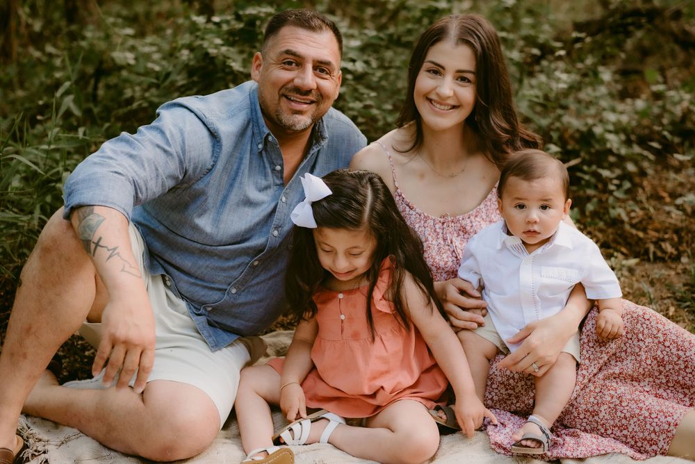 Happy family sitting together on ground in forest setting for casual portrait.