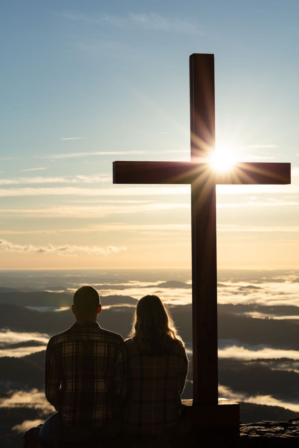 A silhouette of crosses against a sunset sky with clouds rolling below.