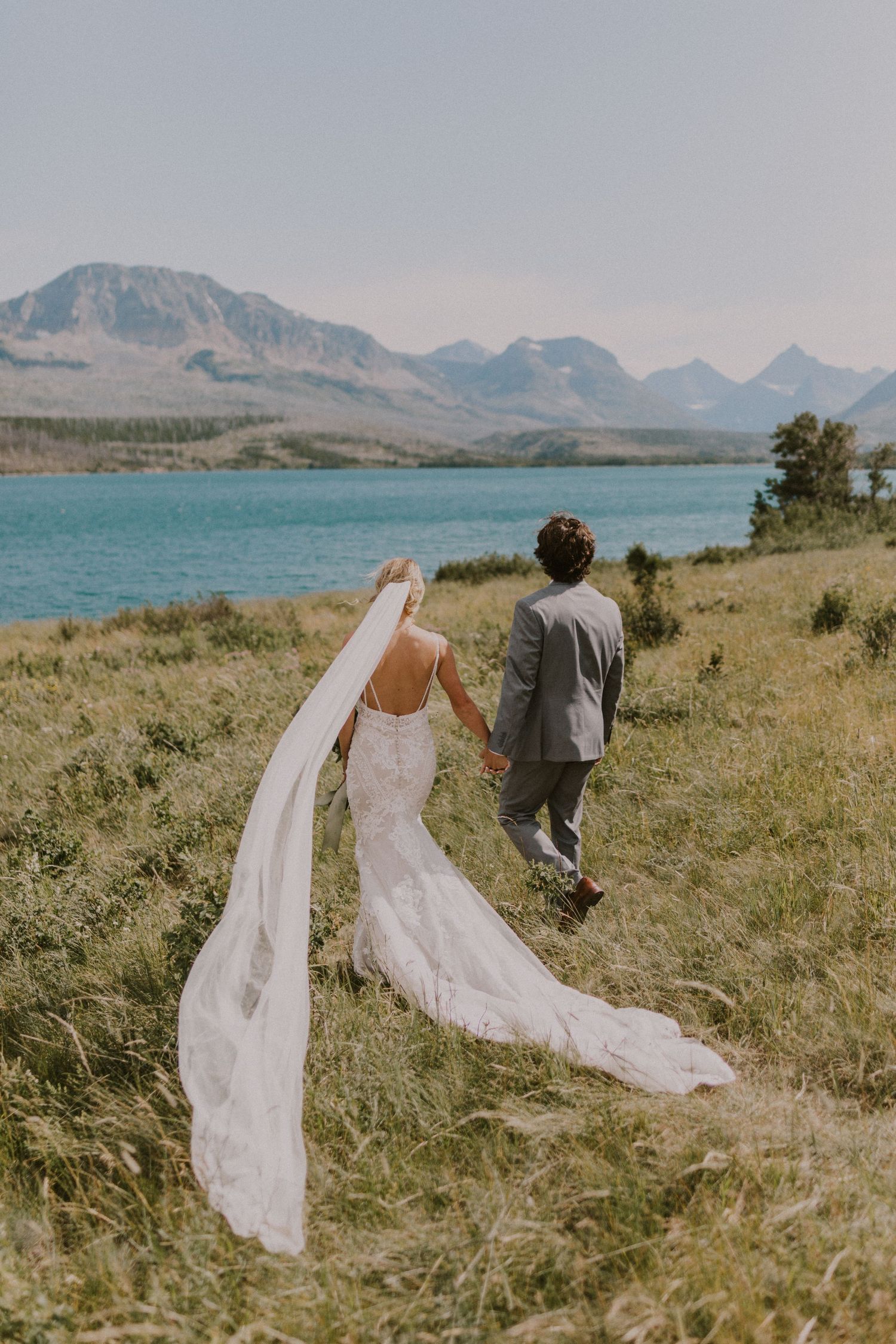 couple in wedding attire walking in Glacier National Park