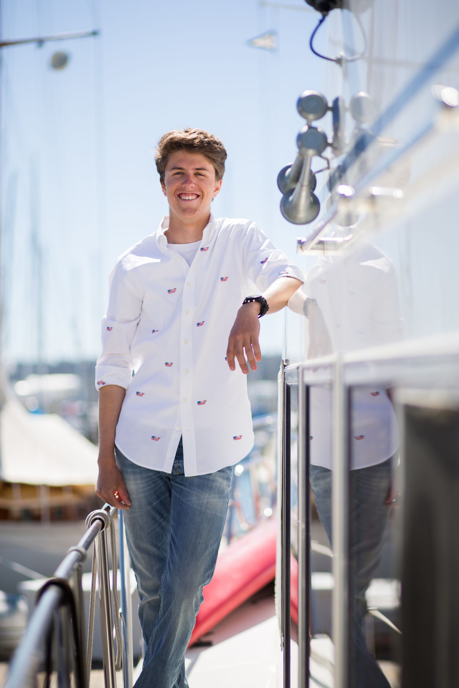 A person in a white patterned shirt leans against railings on a boat dock.
