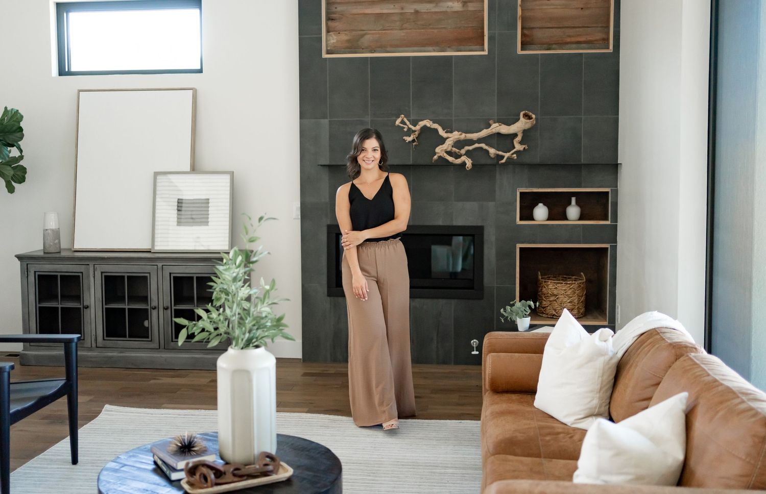 Modern living room featuring a stone fireplace wall, brown leather sofa, and contemporary decor.