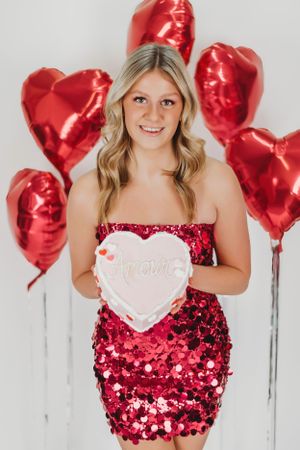 Valentine's themed photo with red heart balloons and sparkly red dress.