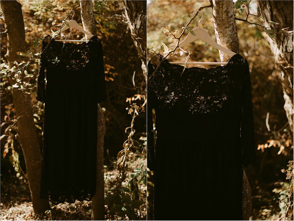 Two elegant black dresses displayed on hangers against a natural forest backdrop.